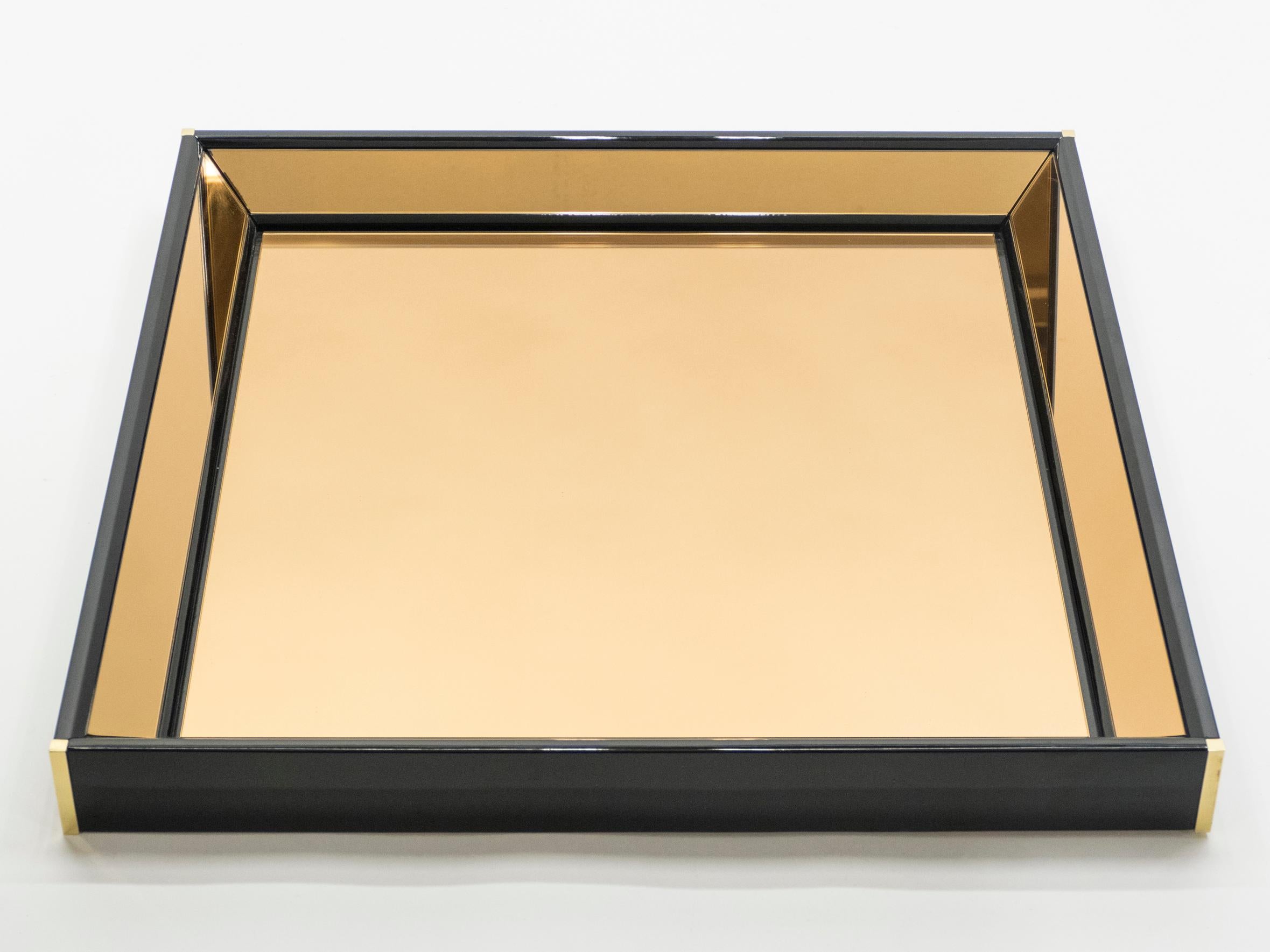 This Italian Hollywood Regency black lacquered mirror would be stunning in any room. The shiny black lacquer coating is the appropriate match to the bronze-tinted mirror frame, both reflecting light in a subdued way and creating a chic color