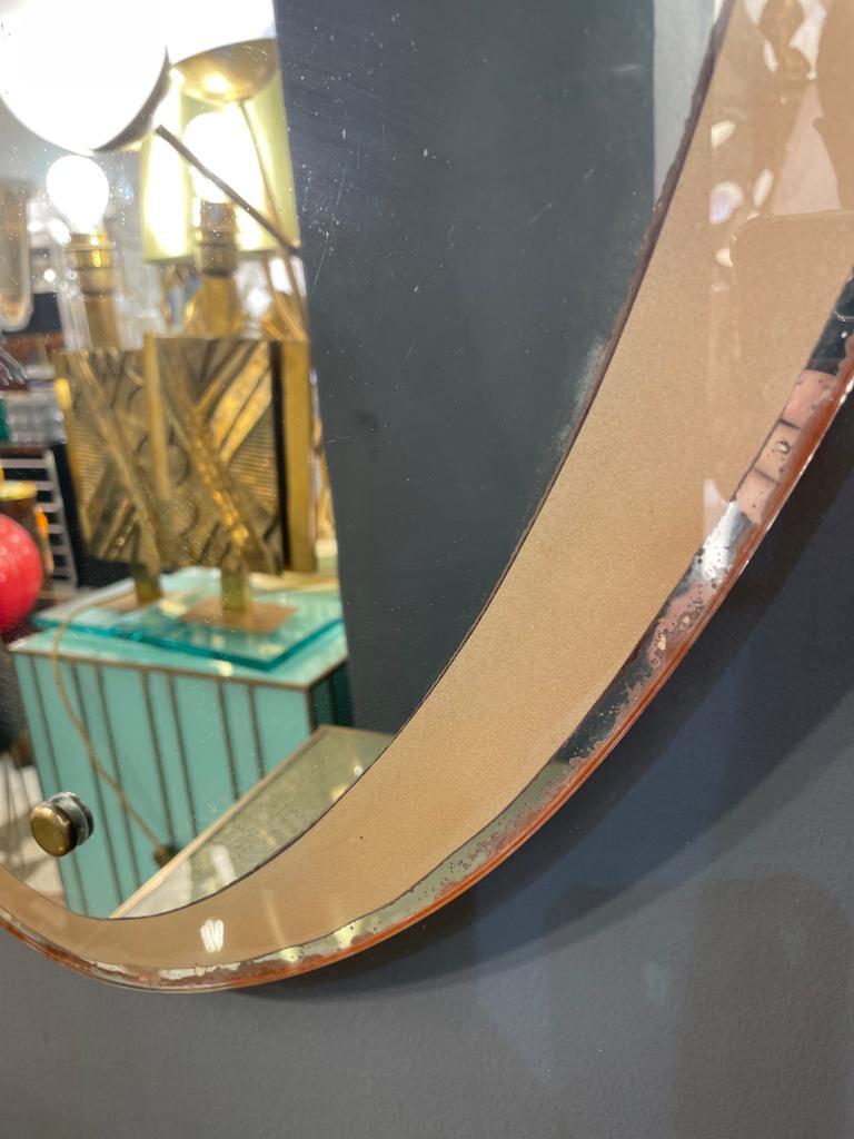 A precious Italian mirror in the shape of a shield with etched glass mounted on a wood frame decorated with faux leather, circa 1940.