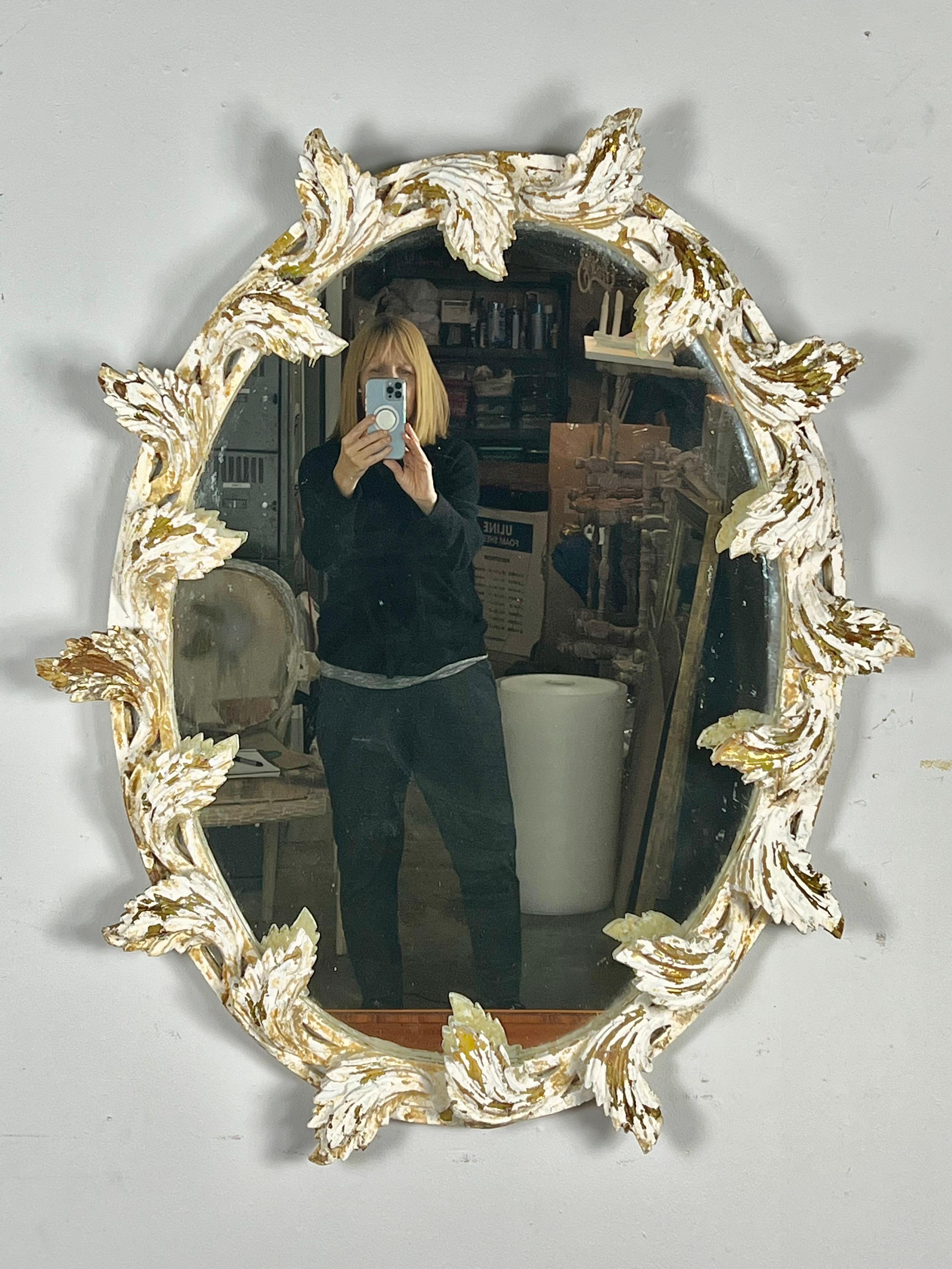 Italienischer geschnitzter Spiegel in ovaler Form mit geschnitzten Blättern. Der Spiegel war ursprünglich aus vergoldetem Holz, hat aber im Laufe der Jahre den größten Teil seines Goldes verloren und den darunter liegenden Gesso freigelegt.
