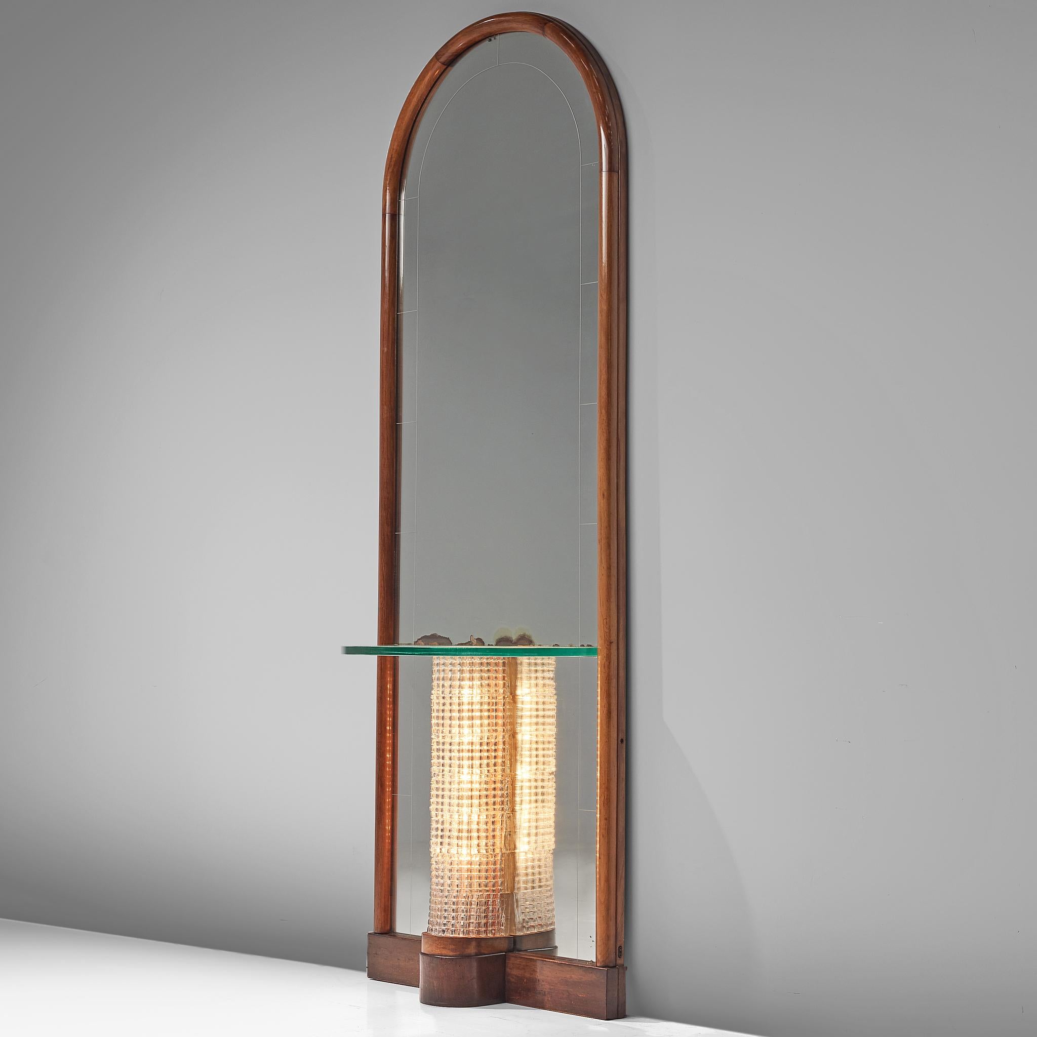 Mirror console, glass and walnut, Italy, circa 1940

Elegant mirror with a rounded top and a walnut frame. Attached in the middle is a small glass console that rests on a glass structured pedestal. A light source is placed with the pedestal,