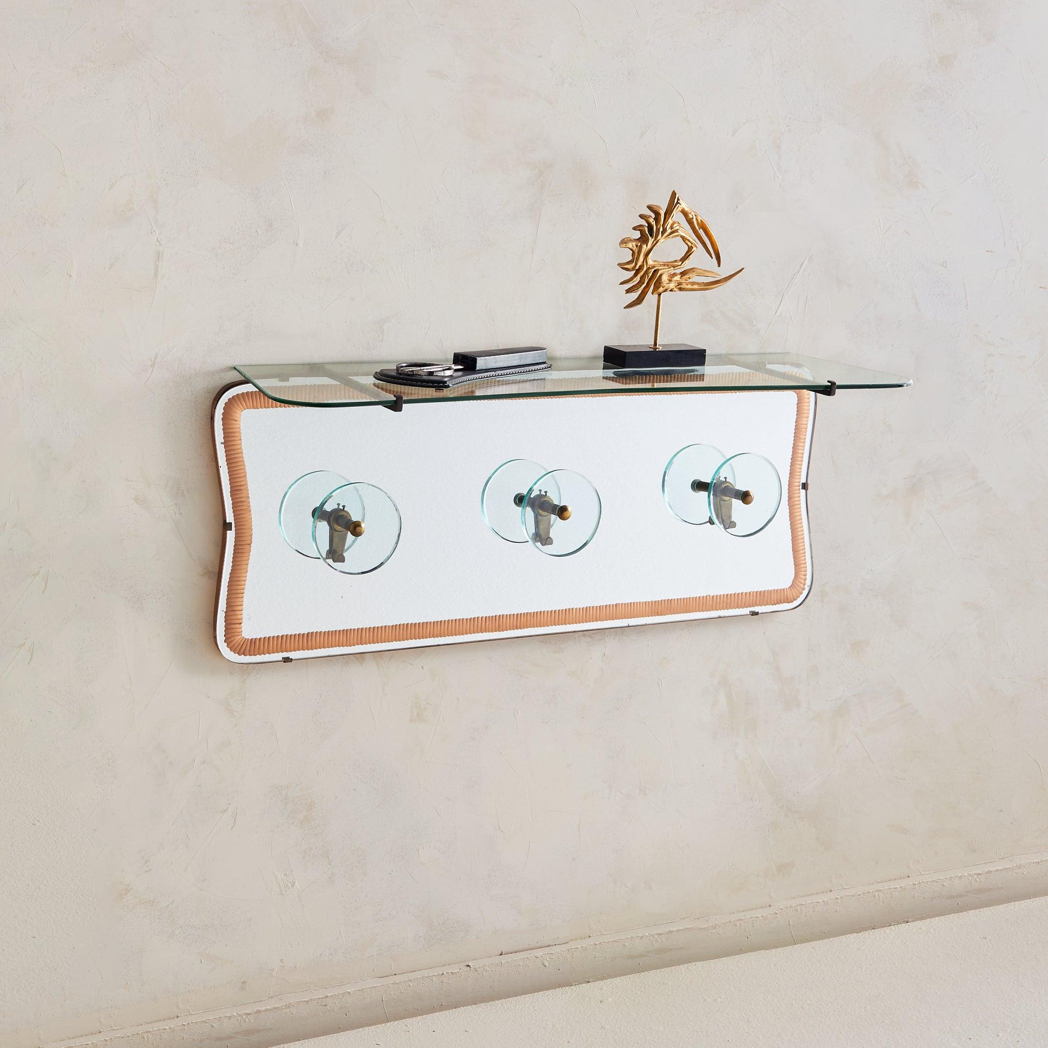 Questo appendiabiti italiano degli anni '70 esemplifica la raffinata maestria dell'epoca. Lo specchio rettangolare, tracciato con un dettaglio in legno smerlato, aggiunge calore all'elegante superficie riflettente. Tre ganci scultorei, arricchiti da