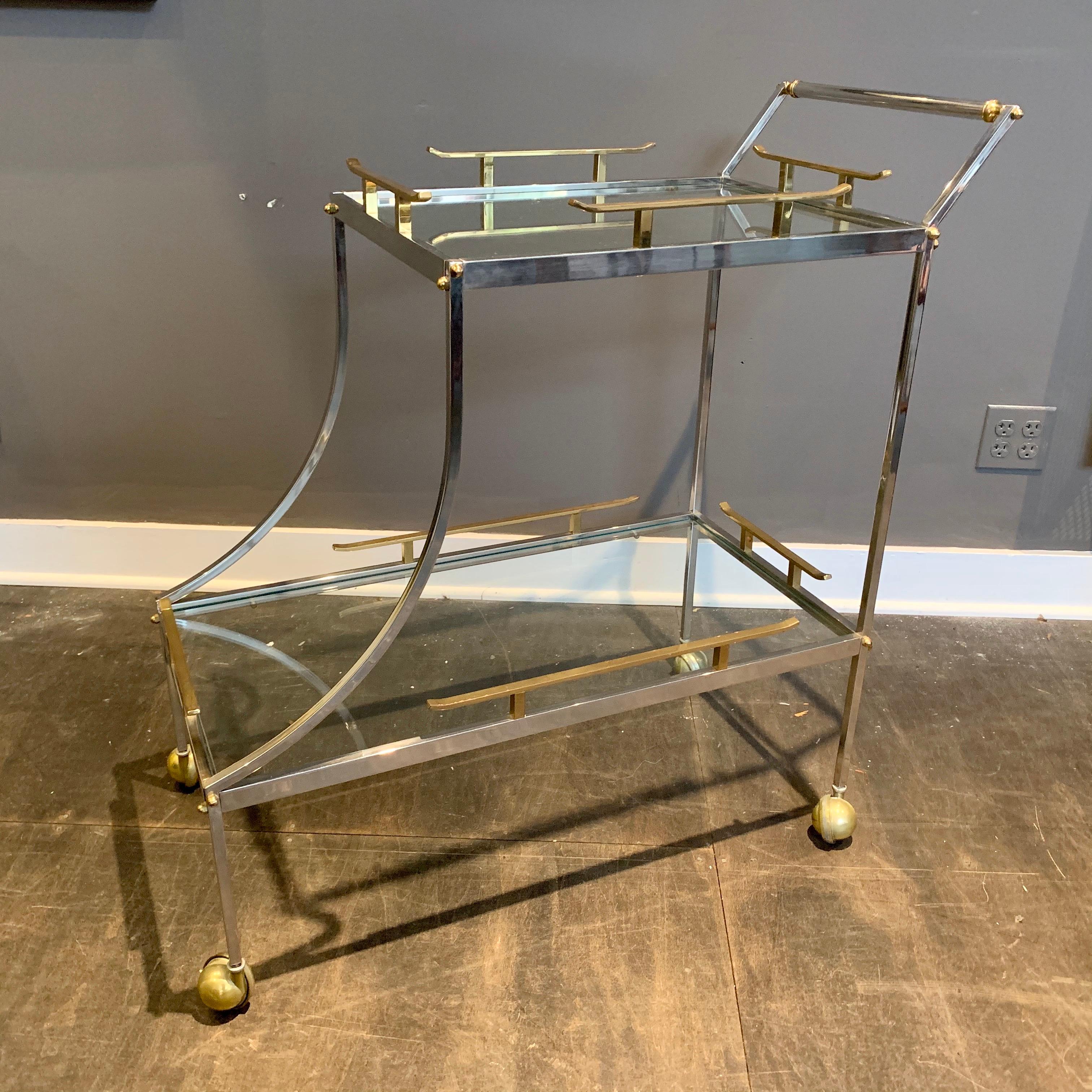 This unique rolling cart features brass and steel on two levels. The upper tier's brass rails and ski-slope style drop to the larger lower tier is what we love about this rolling cart. All original and in wonderful vintage condition.

Note: height