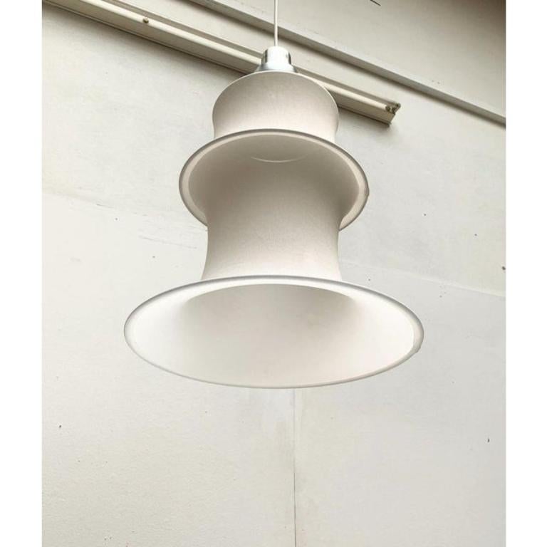 Un classico del design del produttore italiano Danese Milano basato su un disegno di Bruno Munari degli anni '60.

L'elemento più sorprendente di questa lampada è il paralume in tessuto. Il tessuto elasticizzato viene allungato in parte con gli