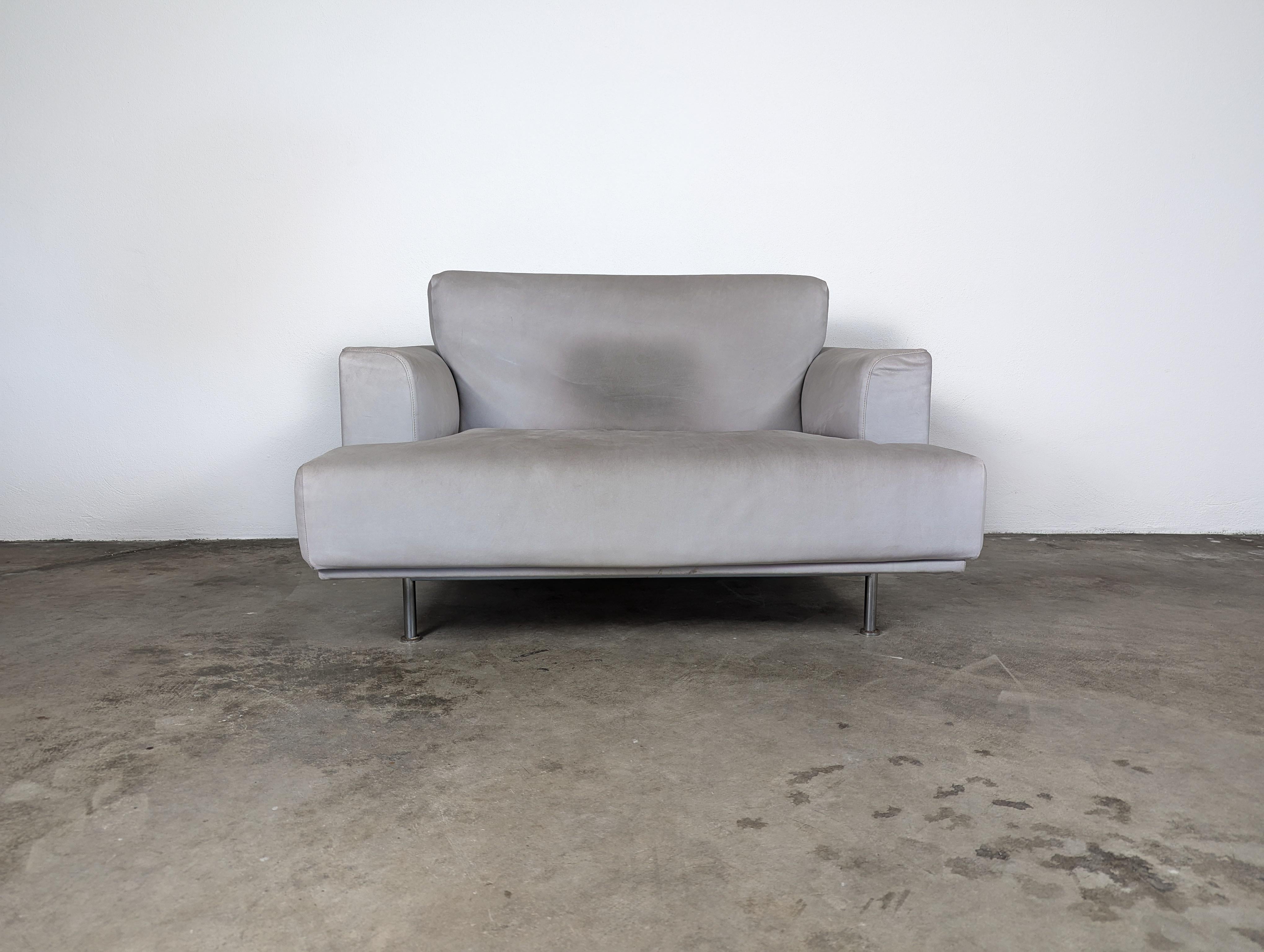 For sale are two exquisite modern chairs designed by the renowned Piero Lissoni for Cassina, the iconic '253' Nest Lounge chairs. These chairs, with their luxurious suede finish and exposed chrome-plated steel frames, embody a harmonious blend of