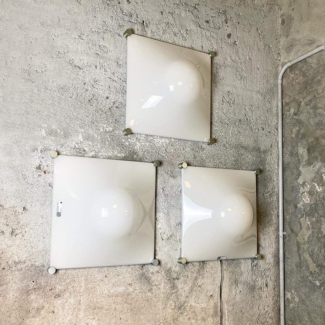 Italian modern set of three aluminum and white plastic wall lamps by Martinelli Luce, 1970s.
Wondertful and vintage set of three wall or ceiling lamps, with square base structure in aluminum and white curved plastic diffuser. Circular detail in
