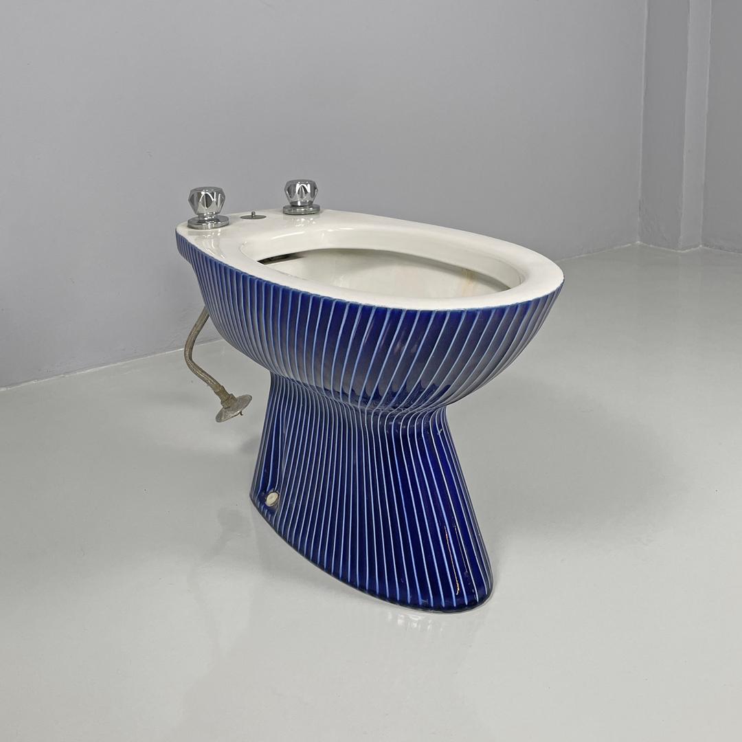 Bidé moderno italiano de cerámica blanca y esmalte azul con rayas blancas, años 70
Bidé de cerámica blanca esmaltada en azul intenso con líneas geométricas decorativas más claras y en relieve. Con dos pomos de metal cromado con caños.
1970s. Número