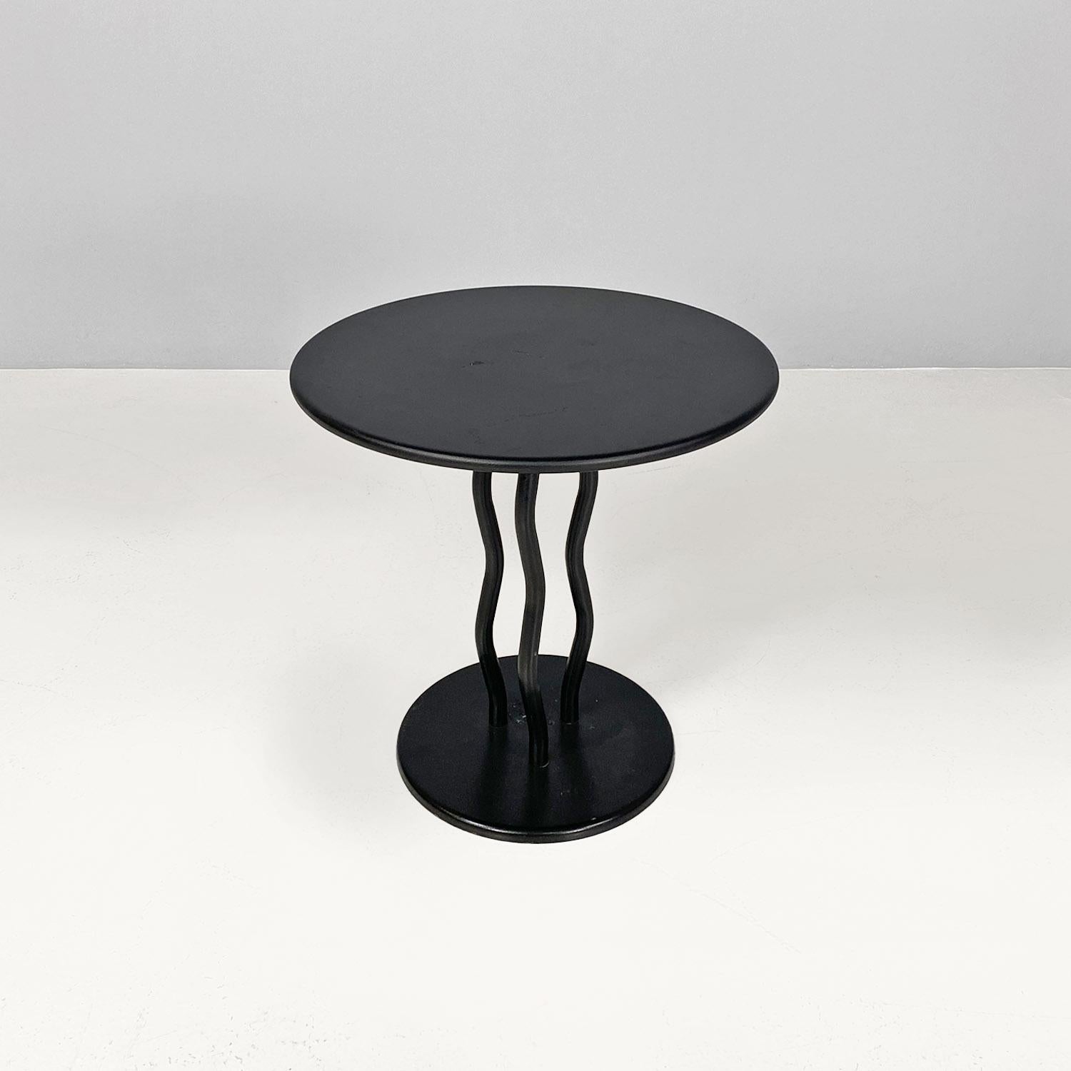 Italian modern black metal round coffee table with three vawy legs, 1980s.
Coffee table with round top in black painted metal. The structure is composed of a round top supported by 3 undulating tubular legs and a single round foot, in black painted