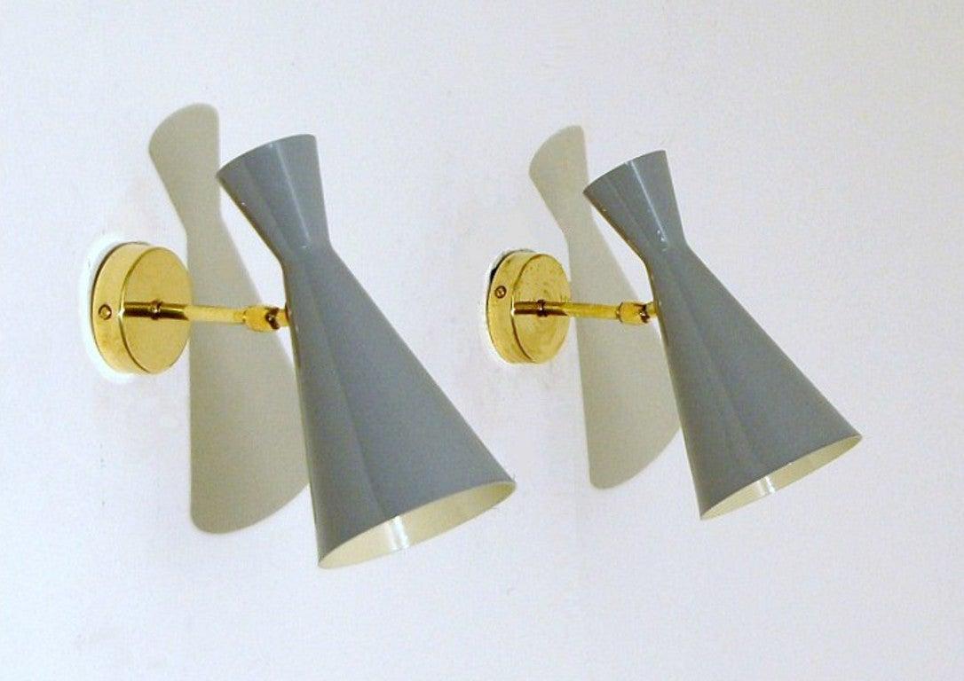 The wall sconce or reading light shown in unlacquered natural brass and gray enamel fabricated in Italy by Fabio Ltd. 

Swiveling head allows for cone adjustment.
Enamel color may be specified by any RAL color code. Our standard enamel colors are