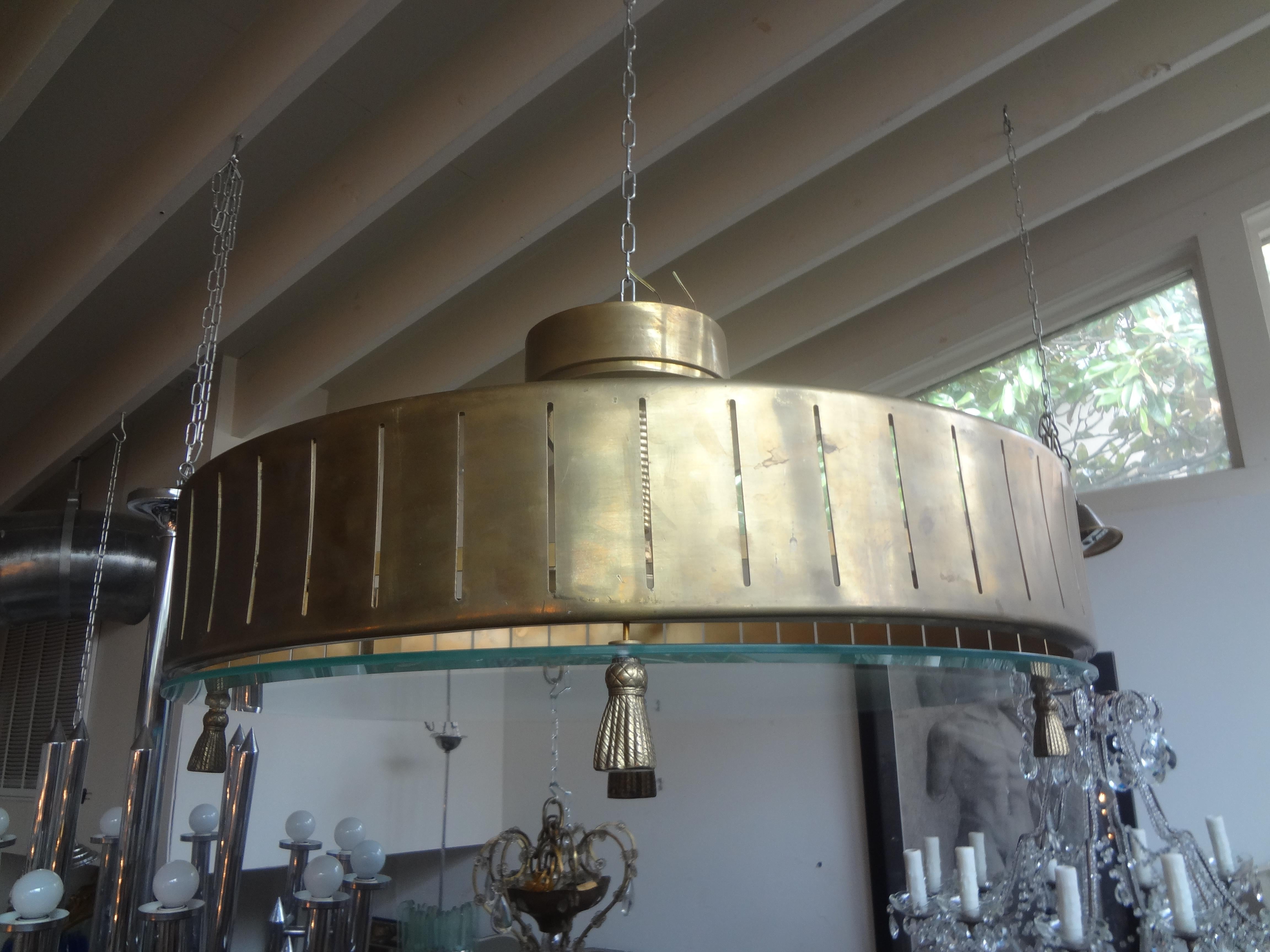 Italian Modern brass and glass chandelier with tassels.
This stunning and unusual Italian brass chandelier has a frosted glass bottom with tassel detail. Our Italian Art Deco inspired brass chandelier has been newly wired with new sockets for the
