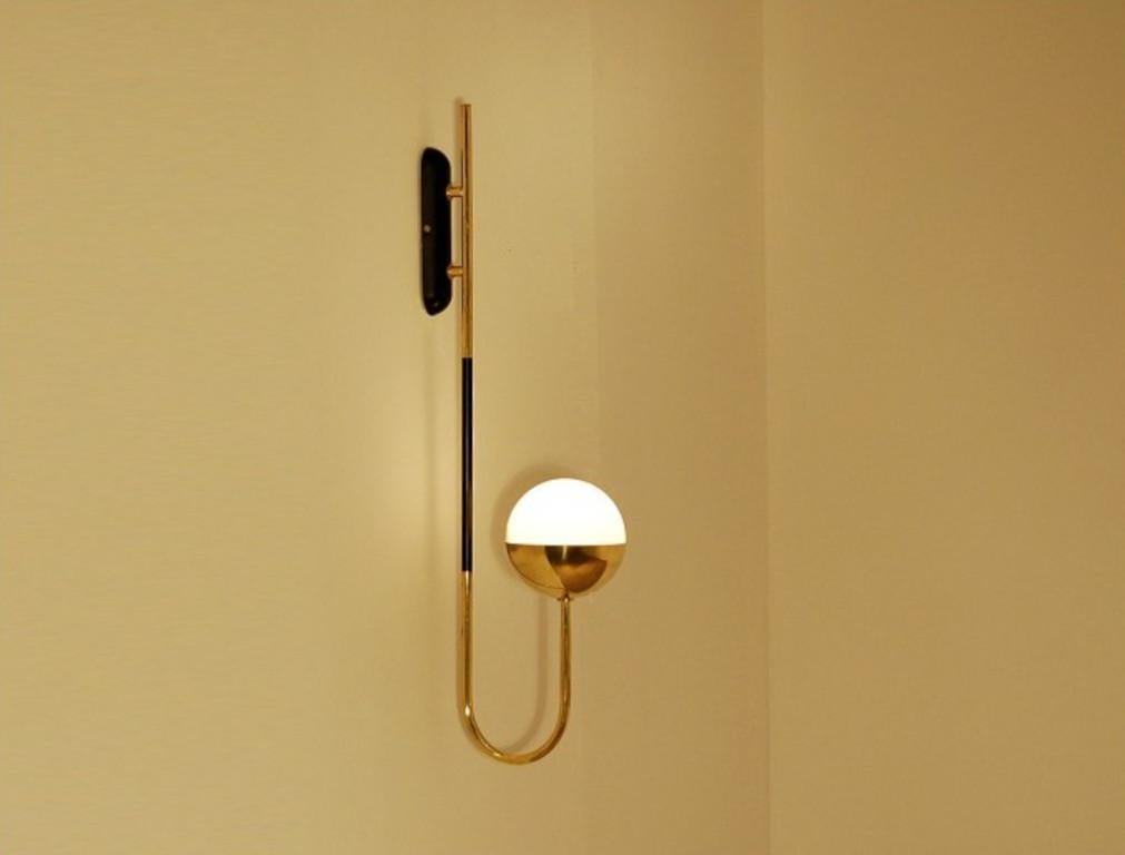 Elegante aplique de pared de latón natural sin lacar con globo de cristal opalino lechoso fabricado en Italia por Fabio Ltd. 

Se trata de una interpretación moderna y contemporánea de un aplique clásico, muy influida por el Modernismo italiano de
