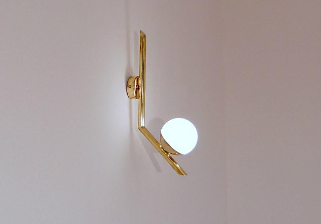 Elegante applique in ottone naturale non laccato con globo in vetro opalino lattiginoso prodotta in Italia da Fabio LTD. 

Si tratta di un'interpretazione moderna e contemporanea di un'applique classica, fortemente influenzata dal modernismo