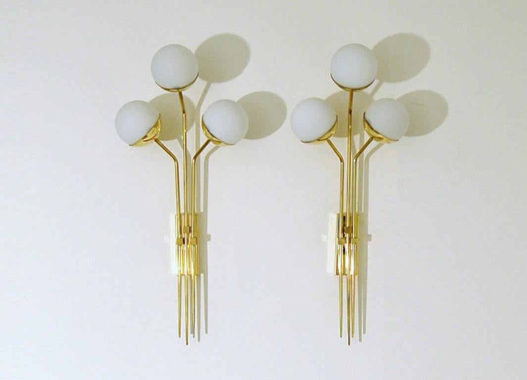 Elegant wall light shown in unlacquered natural brass with opaline milky glass globes fabricated in Italy by Fabio Ltd. 

This is a modern, contemporary interpretation of a classic wall light, strongly influenced by Italian Mid-Century Modernism