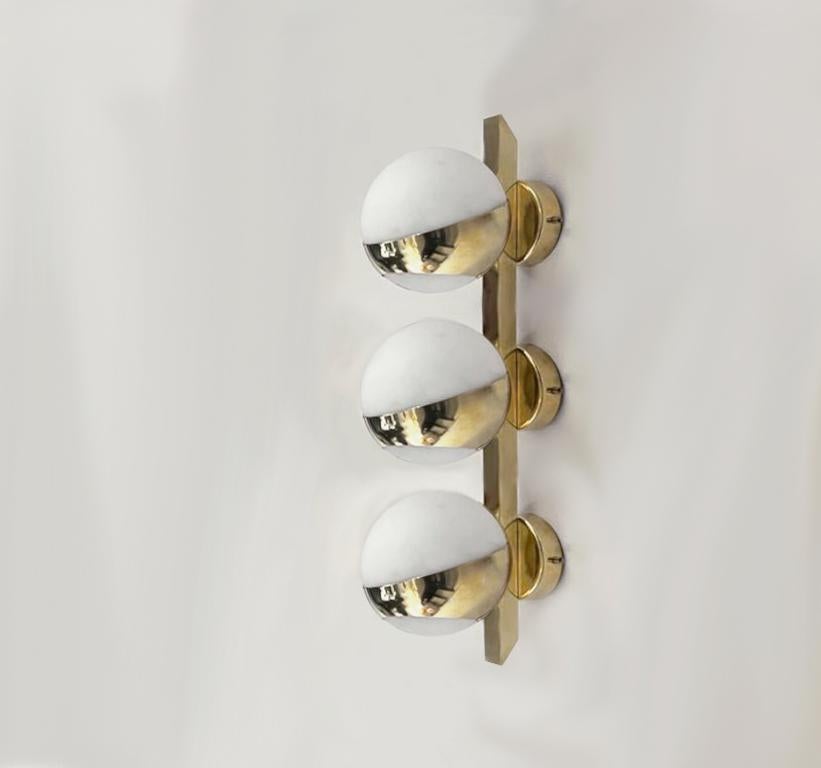Elegant wall light shown in un-lacquered natural brass with opaline milky glass globes fabricated in Italy by Fabio Ltd. 

This is a modern, contemporary interpretation of a classic wall light, strongly influenced by Italian Mid-Century Modernism