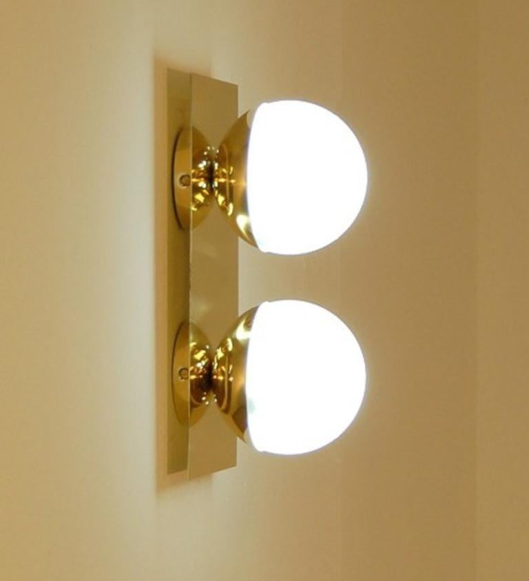 Elegante aplique o empotrable de latón pulido con globos de cristal opalino lechoso fabricado en Italia por Fabio Ltd. 

Se trata de una interpretación moderna y contemporánea de un aplique clásico, muy influida por el Modernismo italiano de