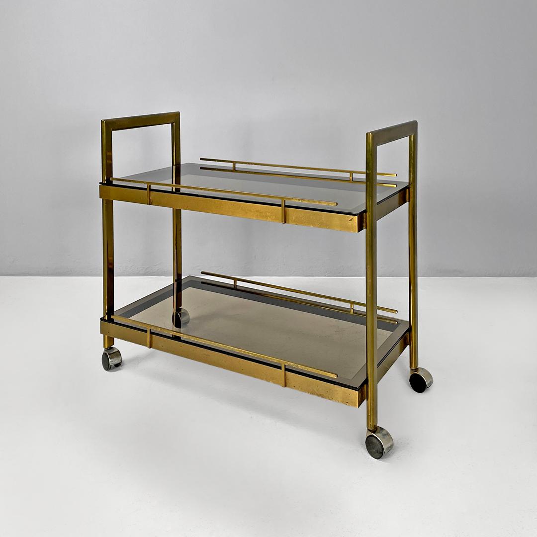 Italian modern brass and smoked glass trolley with handles, 1980s
Trolley on wheels with rectangular base. The structure is in brass with a square section, with two shelves in gray smoked glass. The sides of the structure are raised so as to act as