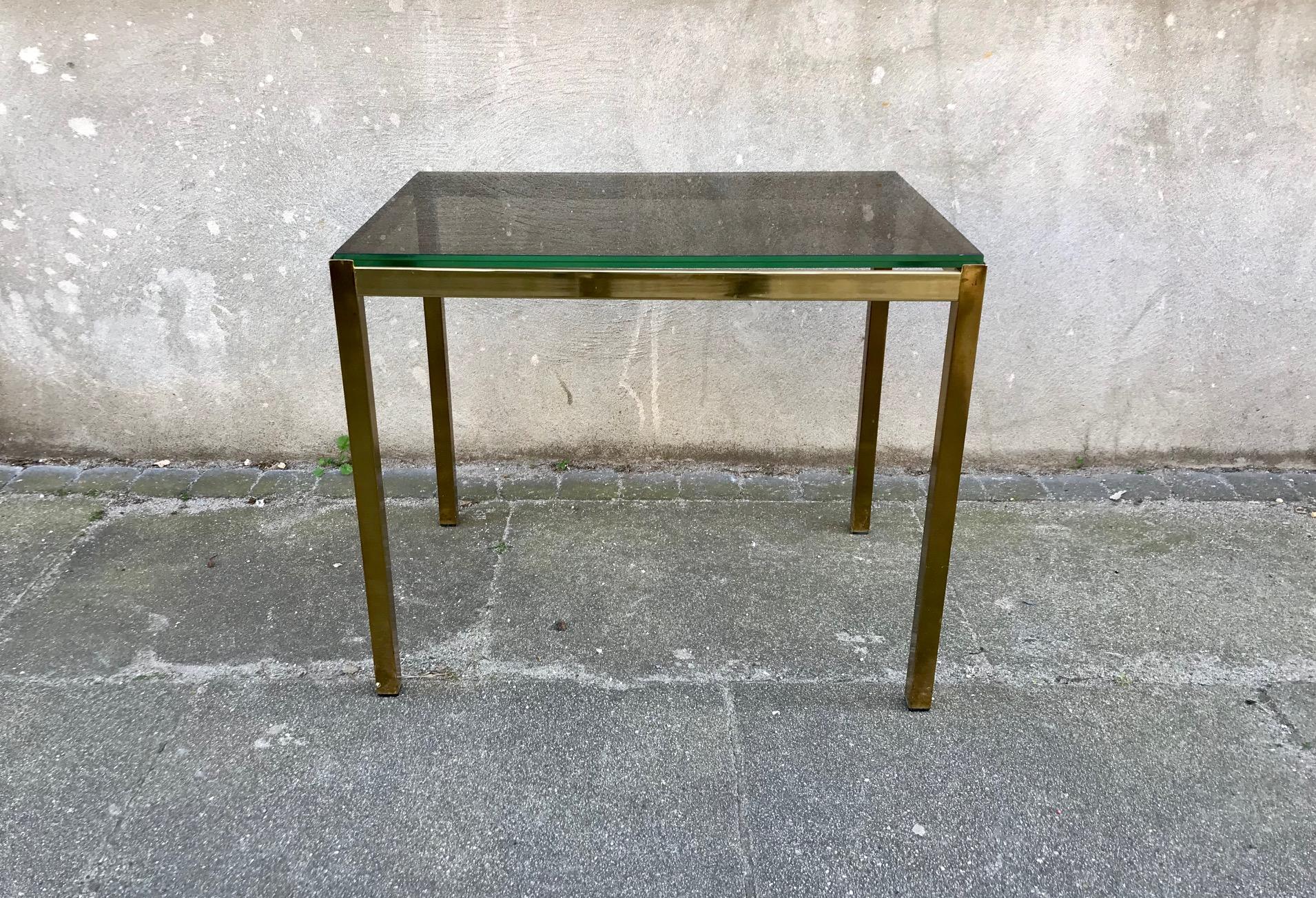 Small coffee table or side/end table. It features a solid brass frame and is topped with a thick smoke glass table top. It was manufactured/designed anonymously in Italy during the 1970s. The design is reminiscent in style to Renato Zevi and Romeo