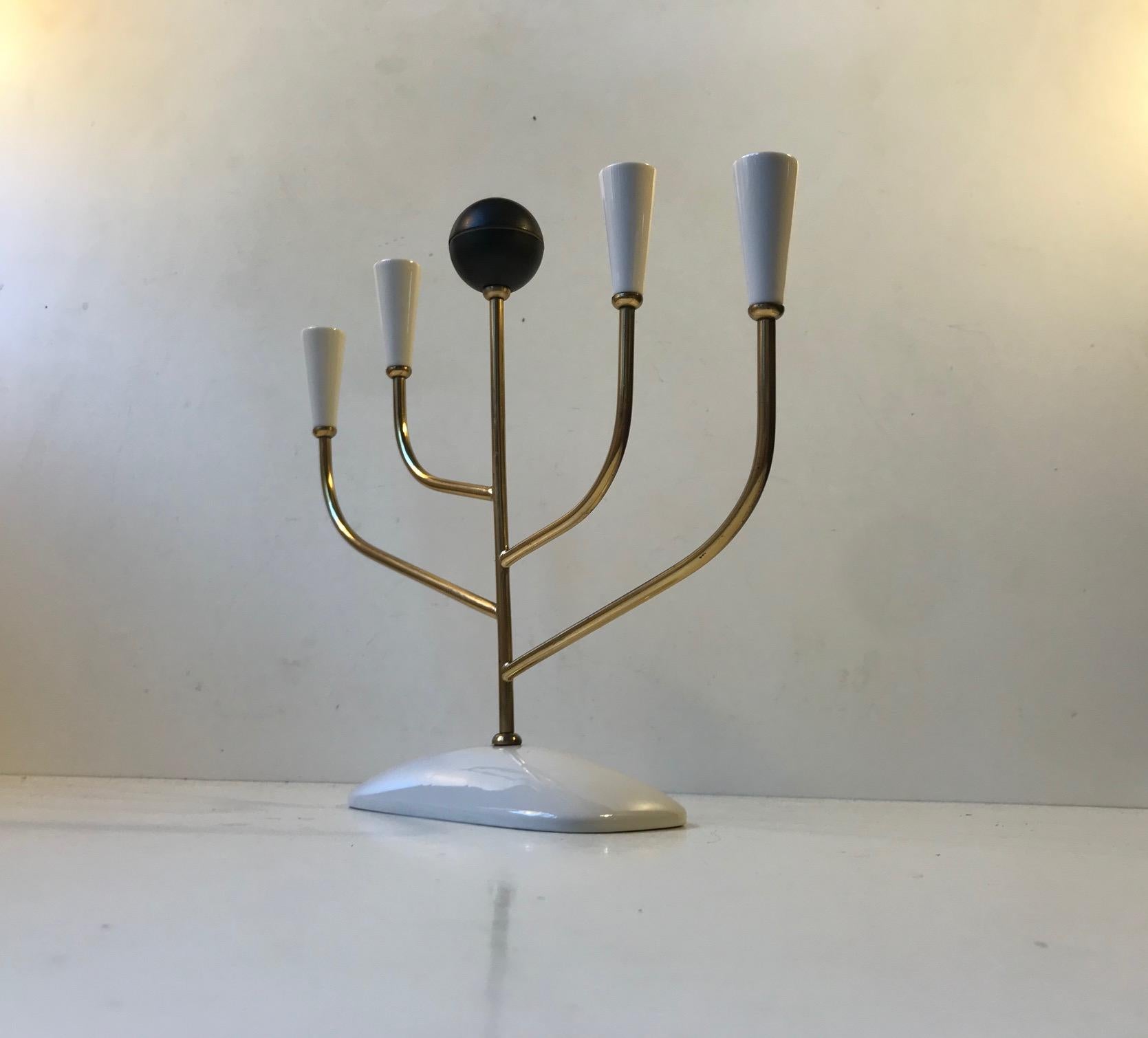 Delicate looking candelabra for small (0.5 inch) candles. It has a practical black 'ball' made of bakelite, a stem in solid brass and the base and 'candle holders' are made from white glazed porcelain. A stylish looking piece made in Italy by an