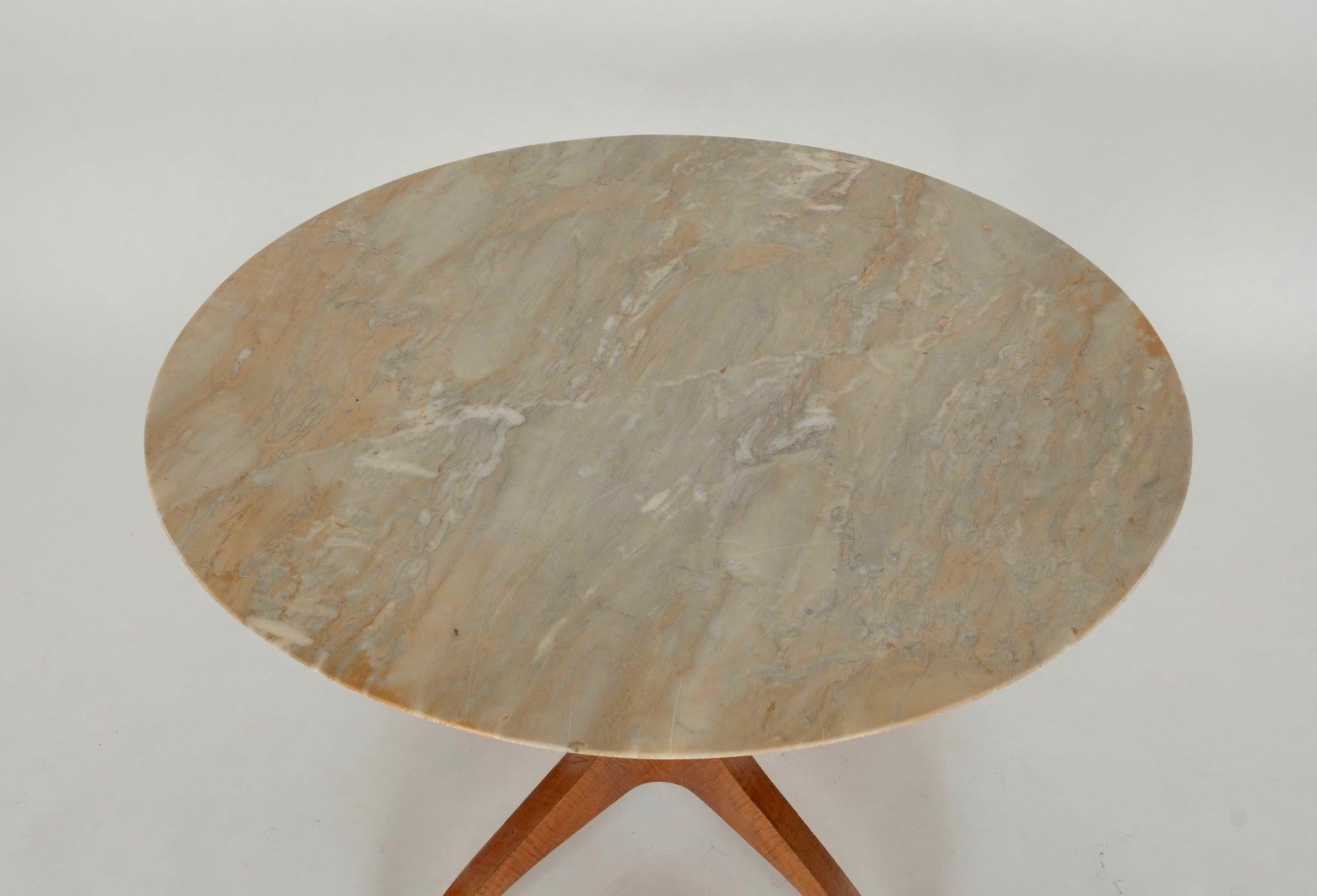 Un sorprendente tavolo da centro di Paolo Buffa. caratterizzato da una base finemente scolpita con dettagli in bronzo e un piano in marmo.

