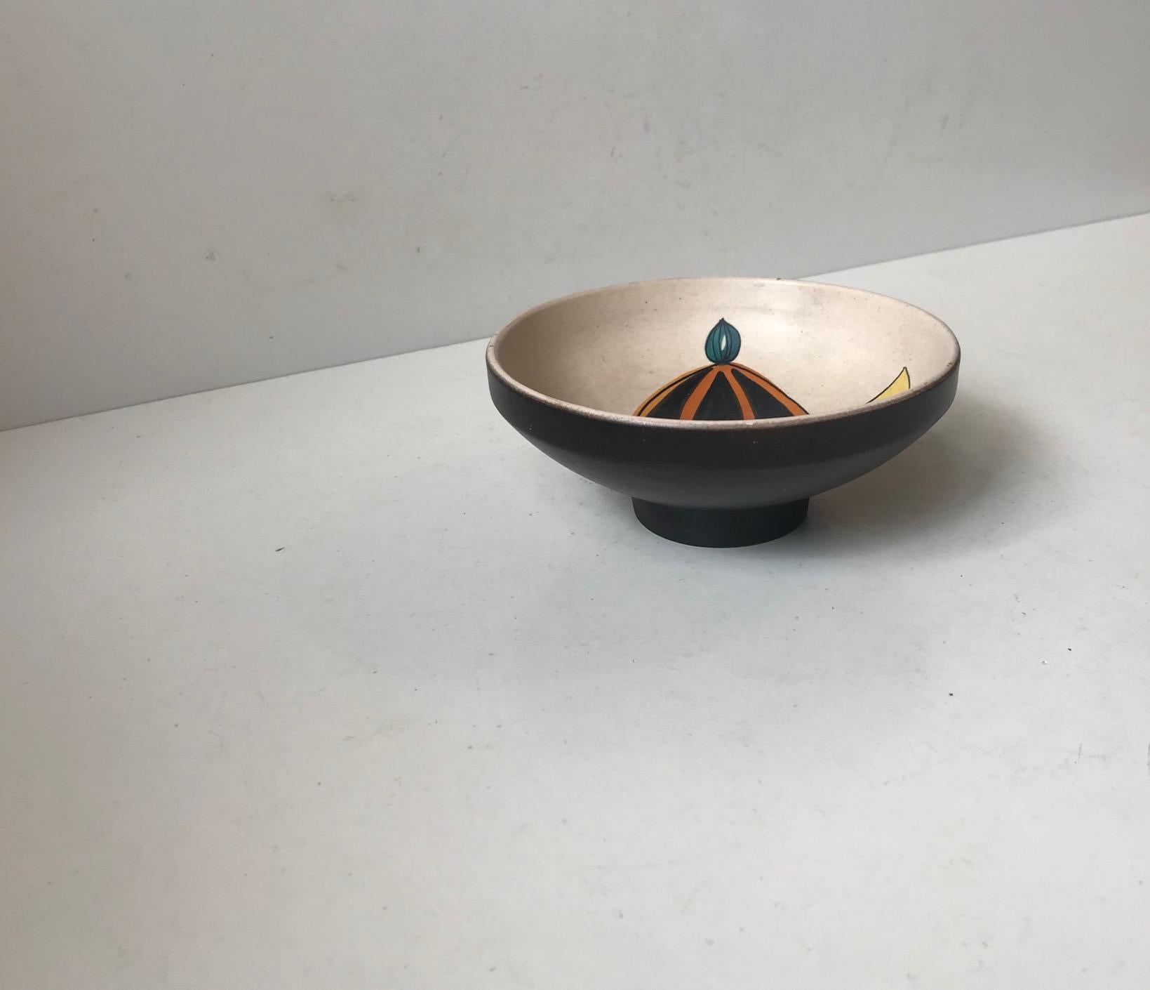 Small footed black ceramic bowl with white interior and a handprinted motif of a Harlequin. Anonymous maker/design. Stamped Italy and has a design number to the base.