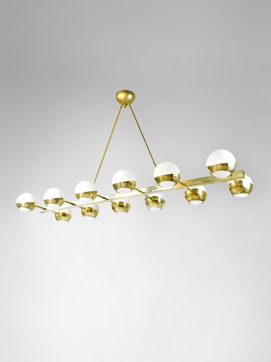 Classic sculptural chandelier shown in un-lacquered natural brass with opaline milky glass globes fabricated in Italy by Fabio Ltd. 

With its modern and linear design, this stunning lamp seamlessly blends into any setting. Made from high-quality