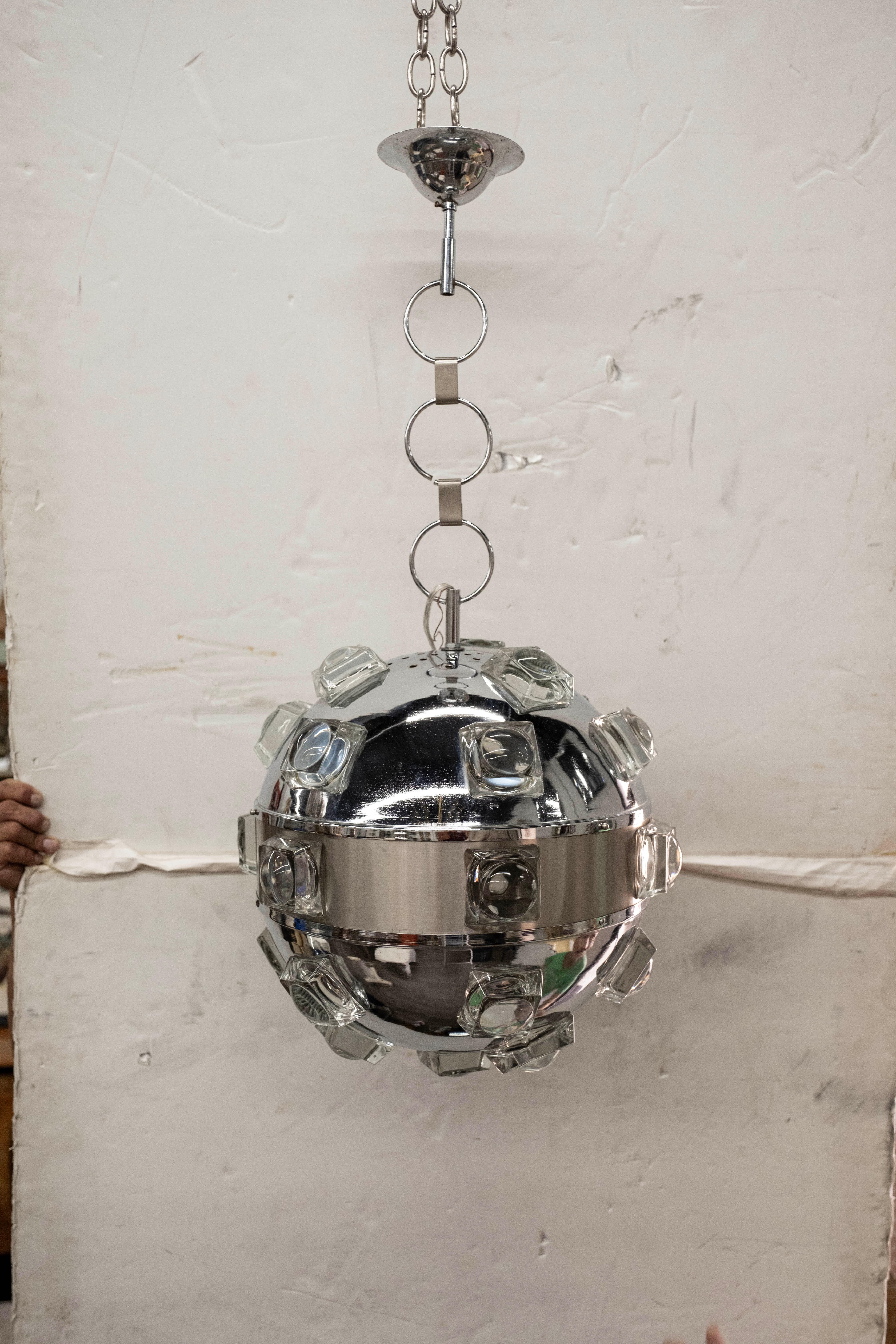 Italian Modern Chrome and Glass Orb Lantern by Oscar Torlasco.
This stunning Italian sphere shaped lantern, pendant or chandelier is comprised of chrome with square glass inserts. It retains the original chrome chain. The chain can be replaced with