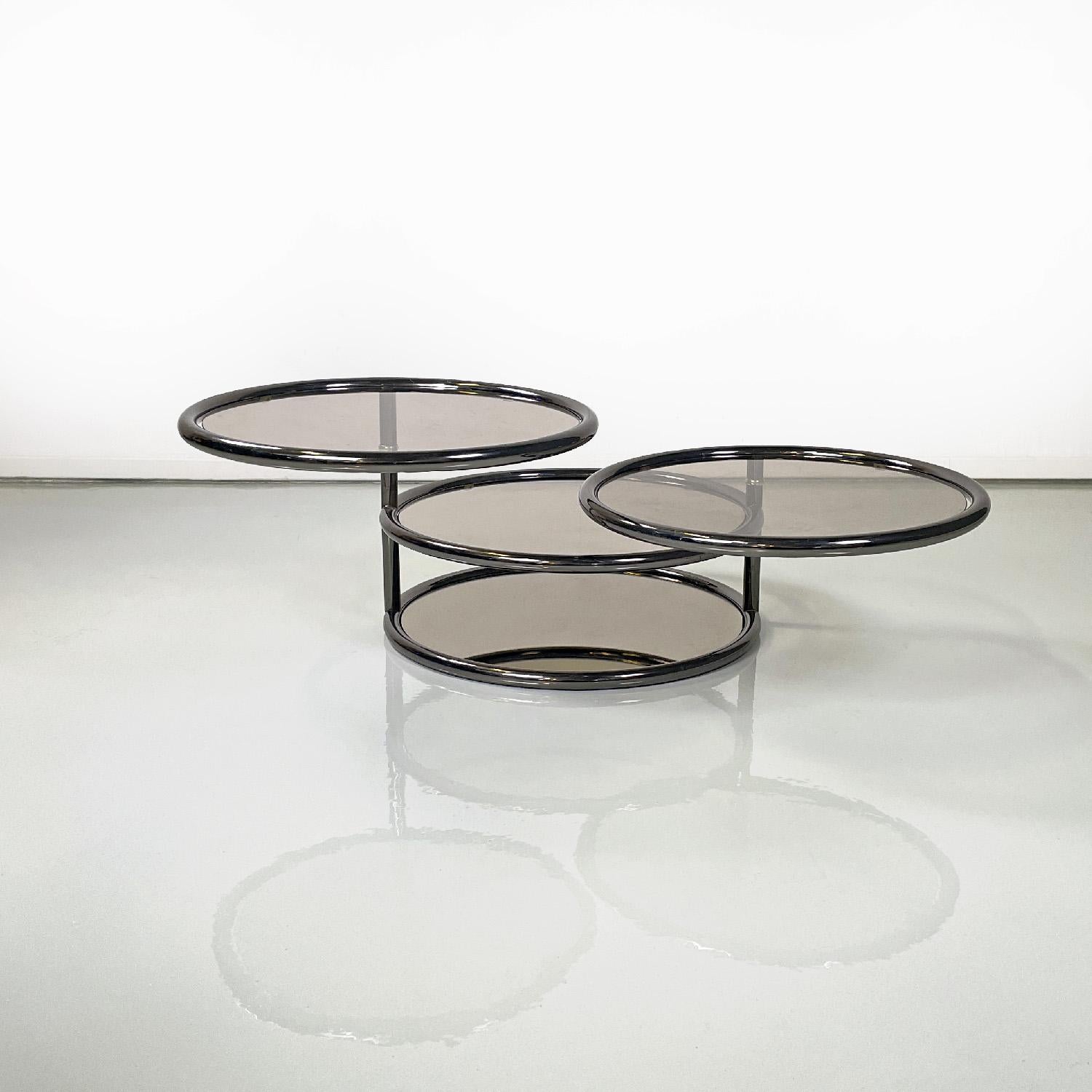 Italian modern coffee table in smoked glass and metal with swivel tops, 1970s
Round base coffee table. The structure is in dark chromed metal tubing, and is composed of four smoked glass shelves, the upper two of which are removable, the lower one