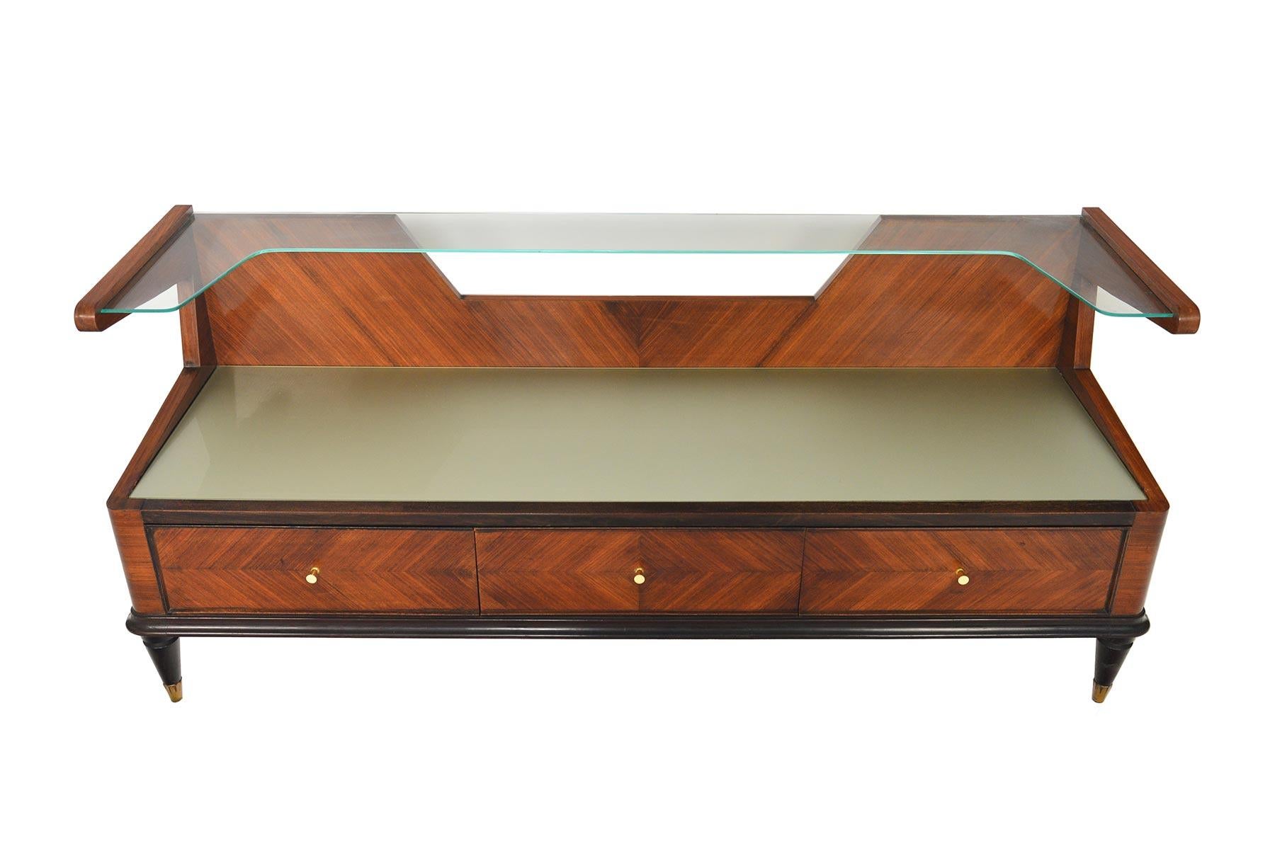 This astounding Italian Mid-Century Modern console credenza offers a streamline silhouette with traditional detailing. The two-tier design features a glass shelf and a frosted glass- lined top. Diamond inlayed rosewood offers stunning symmetry.