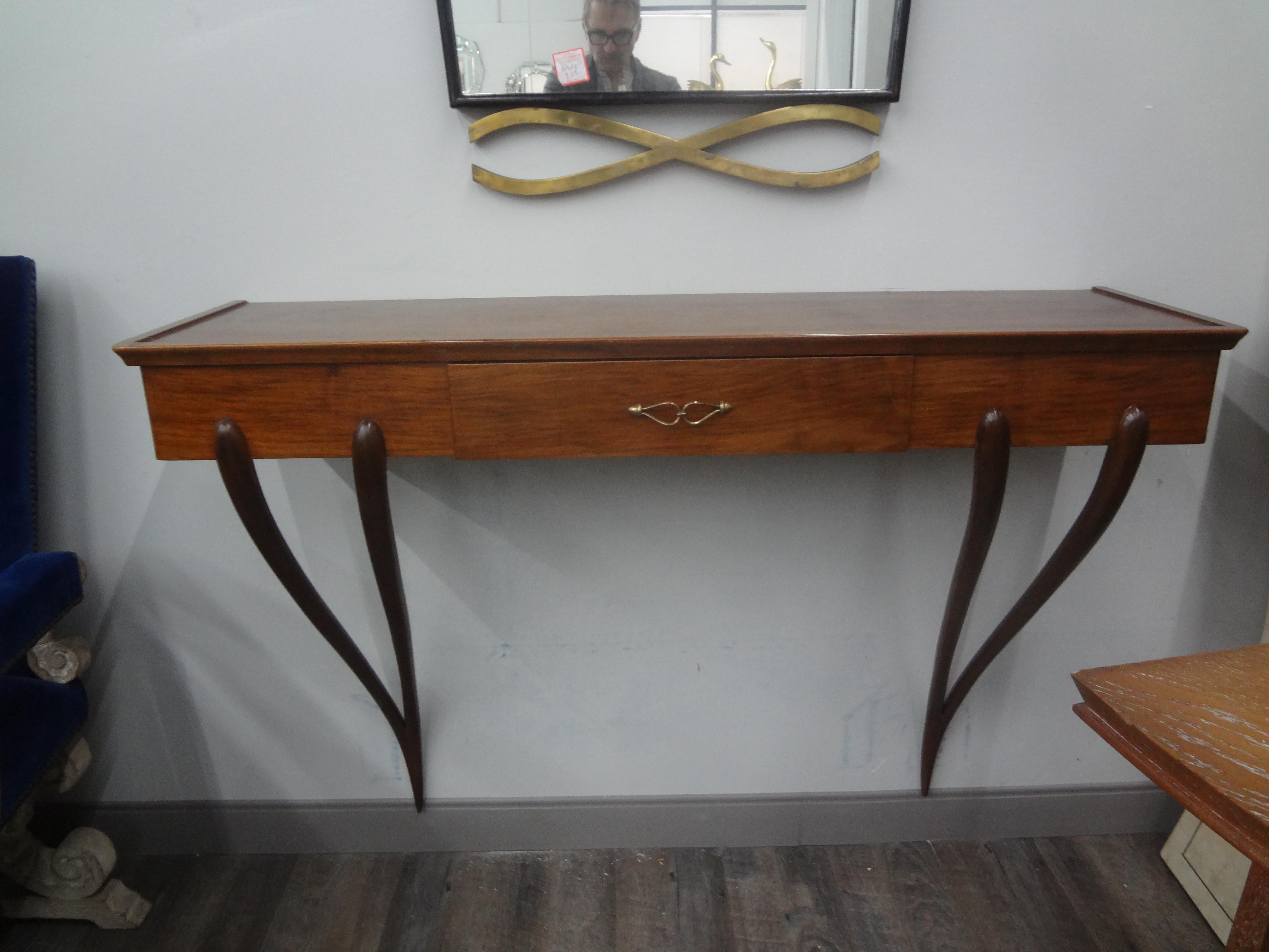Italian modern console table attributed to Paolo Buffa.
This unusual Italian Mid-Century Modern wall mount console made of Italian walnut has ebonized tapered legs, bronze hardware and a single drawer.
Our console has the original clear glass top