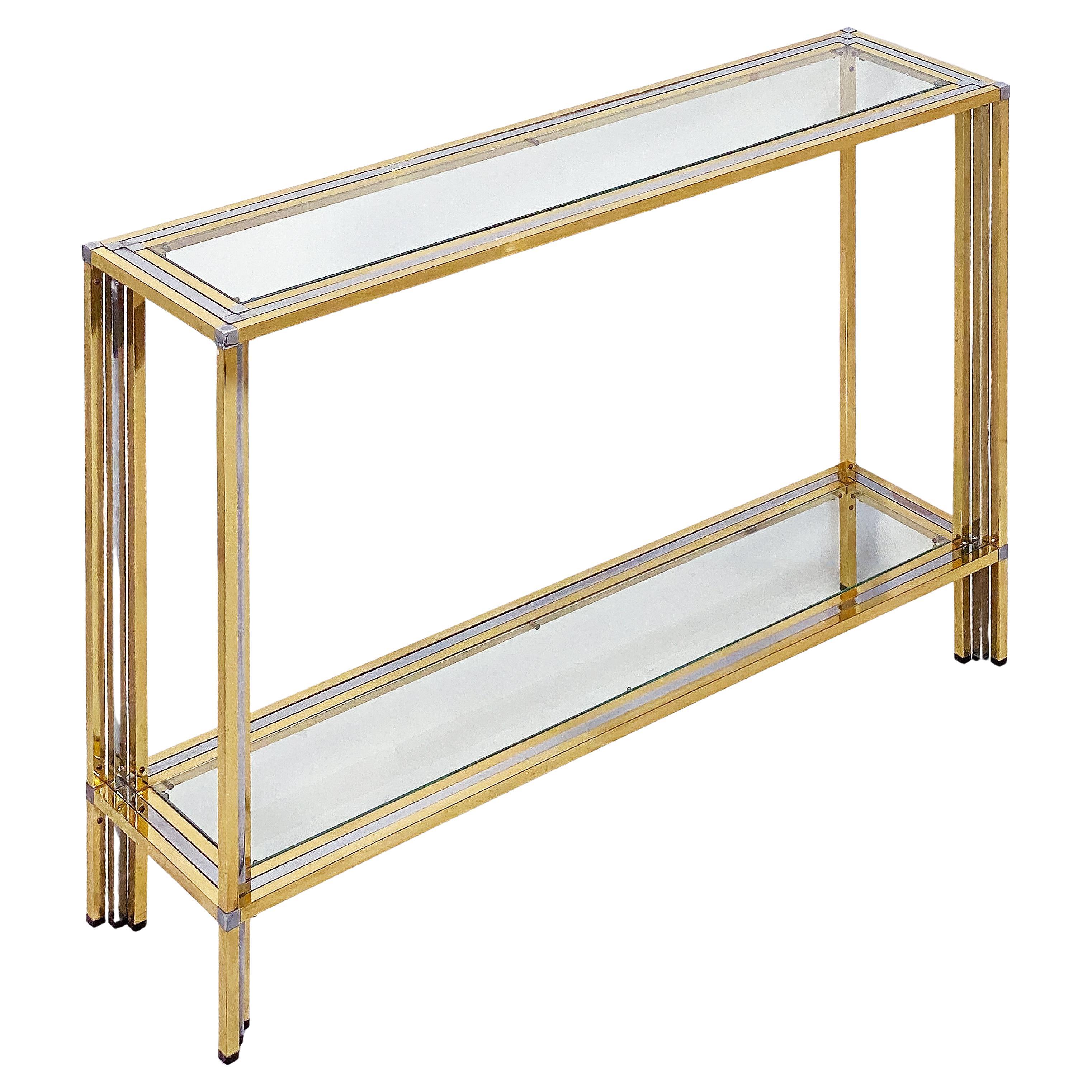 A fine Italian Modern rectangular two-tiered console table of stylish brass and chrome by the celebrated modern designer, Romeo Rega, featuring a top with inset glass over four angled legs with lower shelf of inset glass.

Romeo Rega (1925 – 1984)