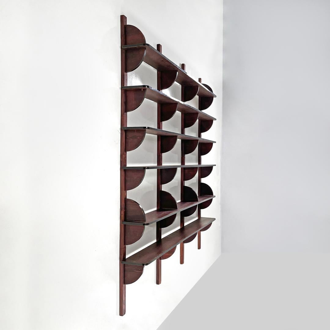 Italian modern dark wood wall bookcase with black plastic details, 1980s
Dark wood wall bookcase. The structure is made up of four uprights and six rows of shelves, the final external part of the shelves is in the shape of a triangle with a curved
