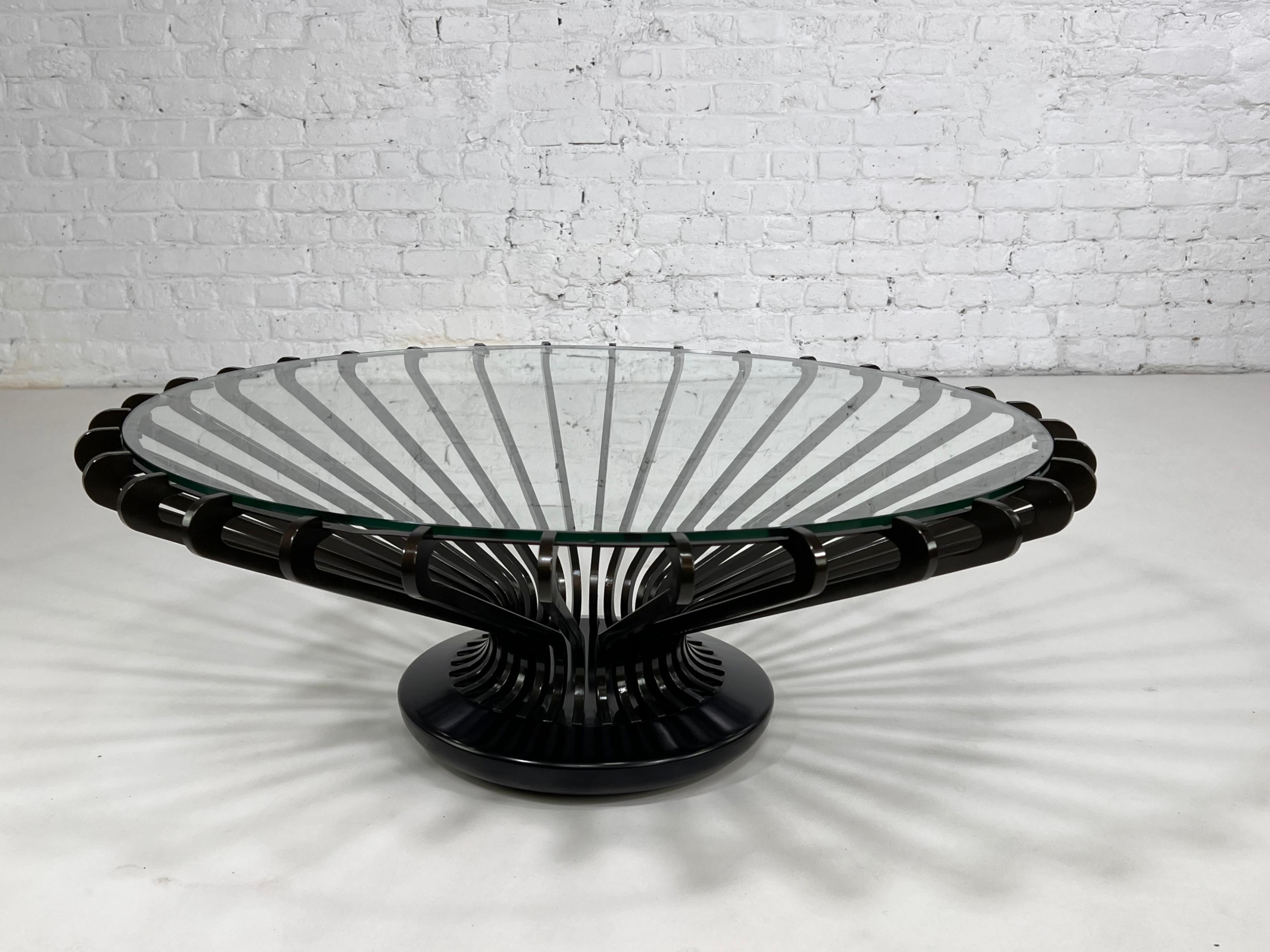 Mesa de centro redonda de metal y cristal, de diseño moderno italiano, con estructura metálica y aérea negra y tapa redonda de cristal.