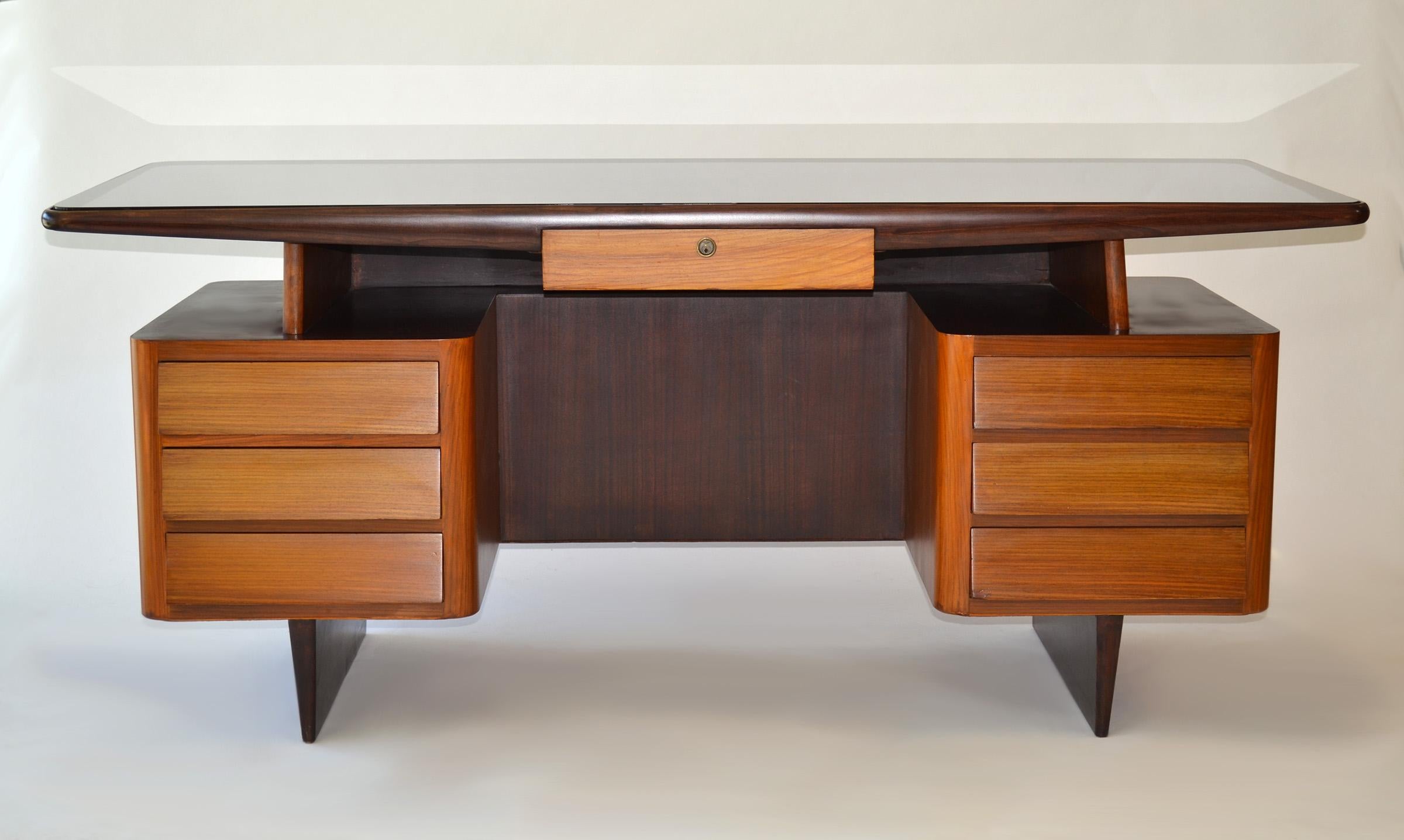Italian Modern Desk attributed to Gio Ponti 1950s
Raised surface writing or executive desk with seven drawers (no key) in mahogany and rosewood veneer, black glass top (likely replaced), brass on Ponti-style fin base. Purchased in France.