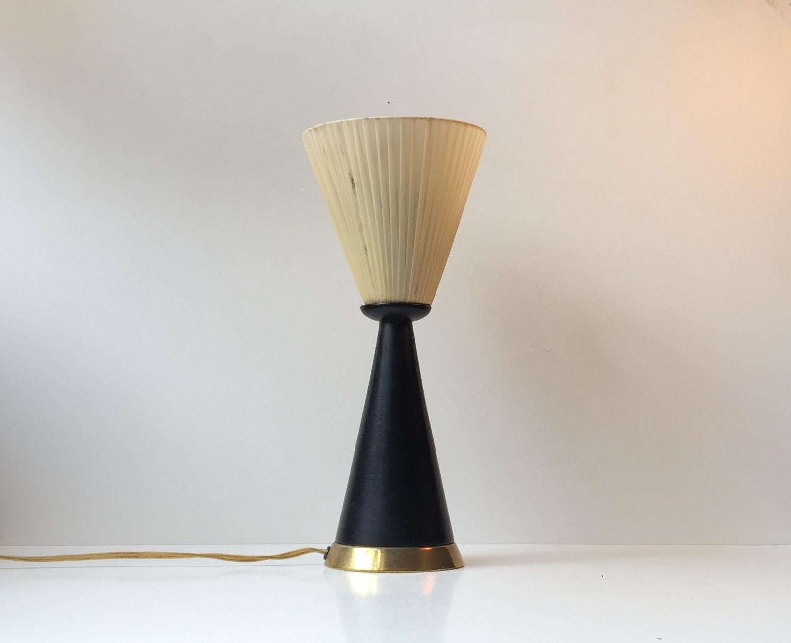 Diablo table light composed of a black lacquered wooden cone, a brass base and a fabric wrapped conical shade. It was manufactured in Italy during the 1960s in a style reminiscent of Stilnovo and Svend Aage Holm Sørensen. Please notice that’s there