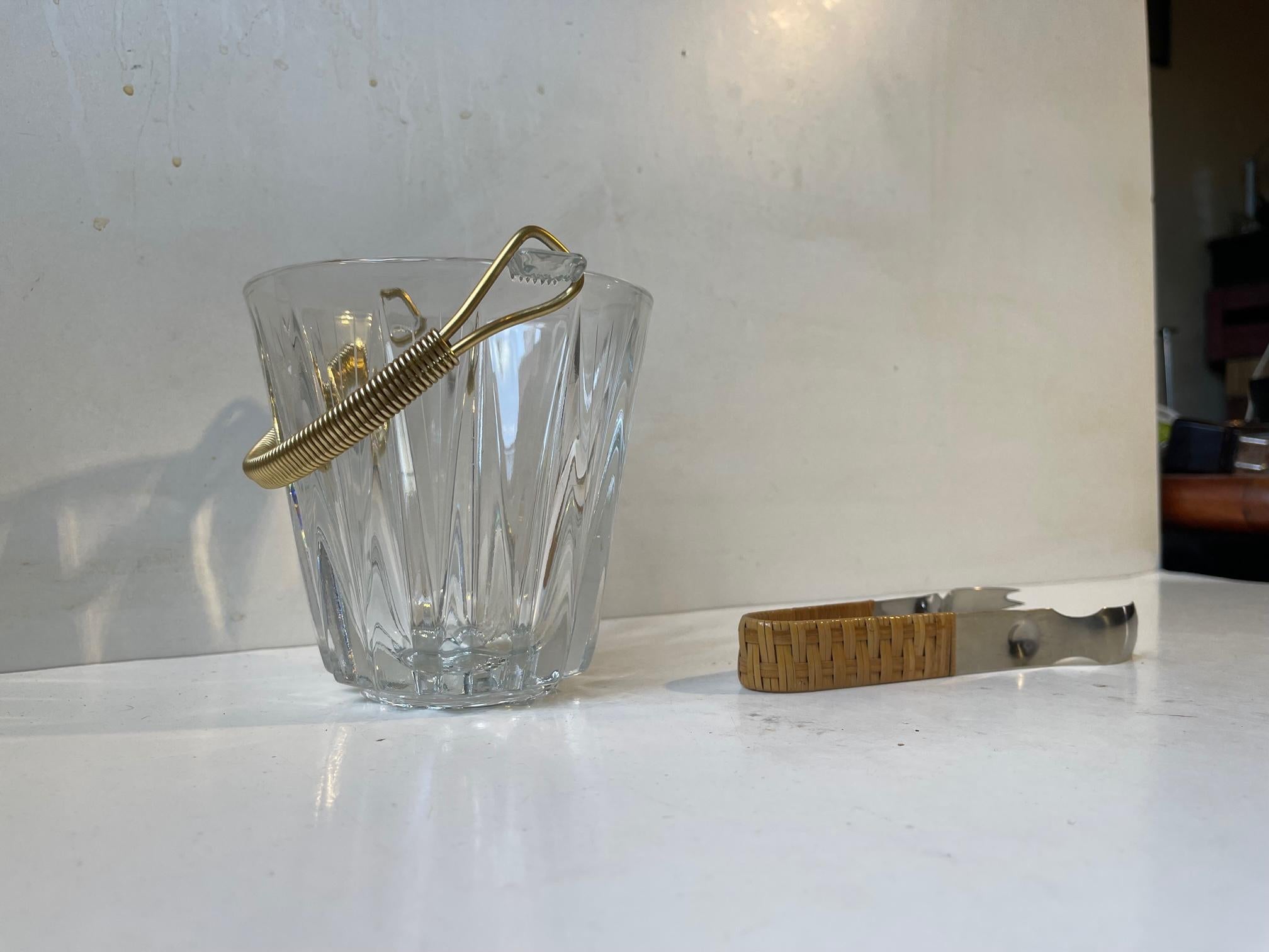 Un seau à glace élégant de petite taille, doté d'une poignée en aluminium anodisé doré et d'une pince en acier inoxydable avec manche en rotin. Le seau à glace a été fabriqué en Italie vers 1960-70. Le tong datant de la même période pourrait être
