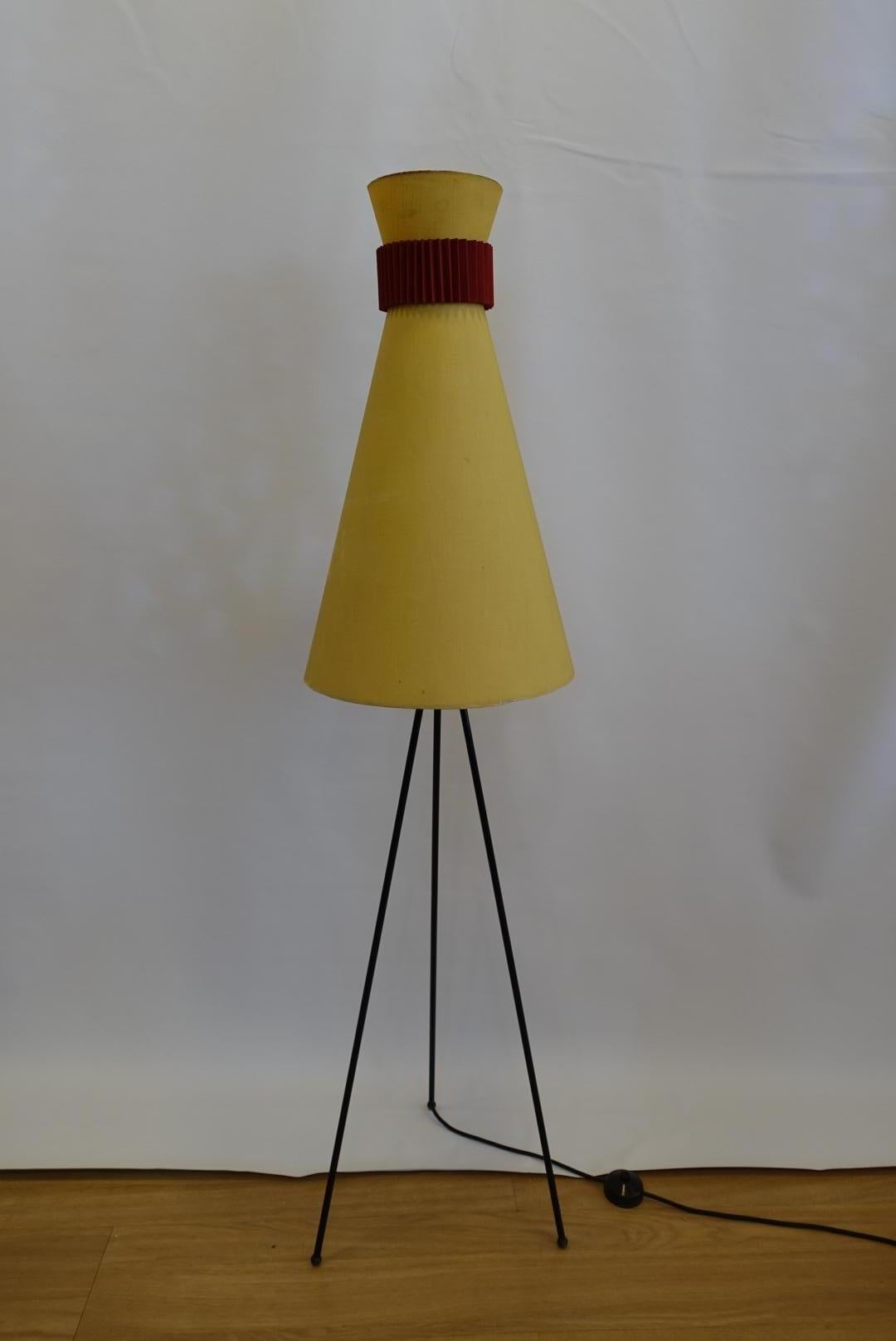 This Italian floor lamp from Luce Plan, features a yellow cotton lampshade and a black metal tripod base.
     