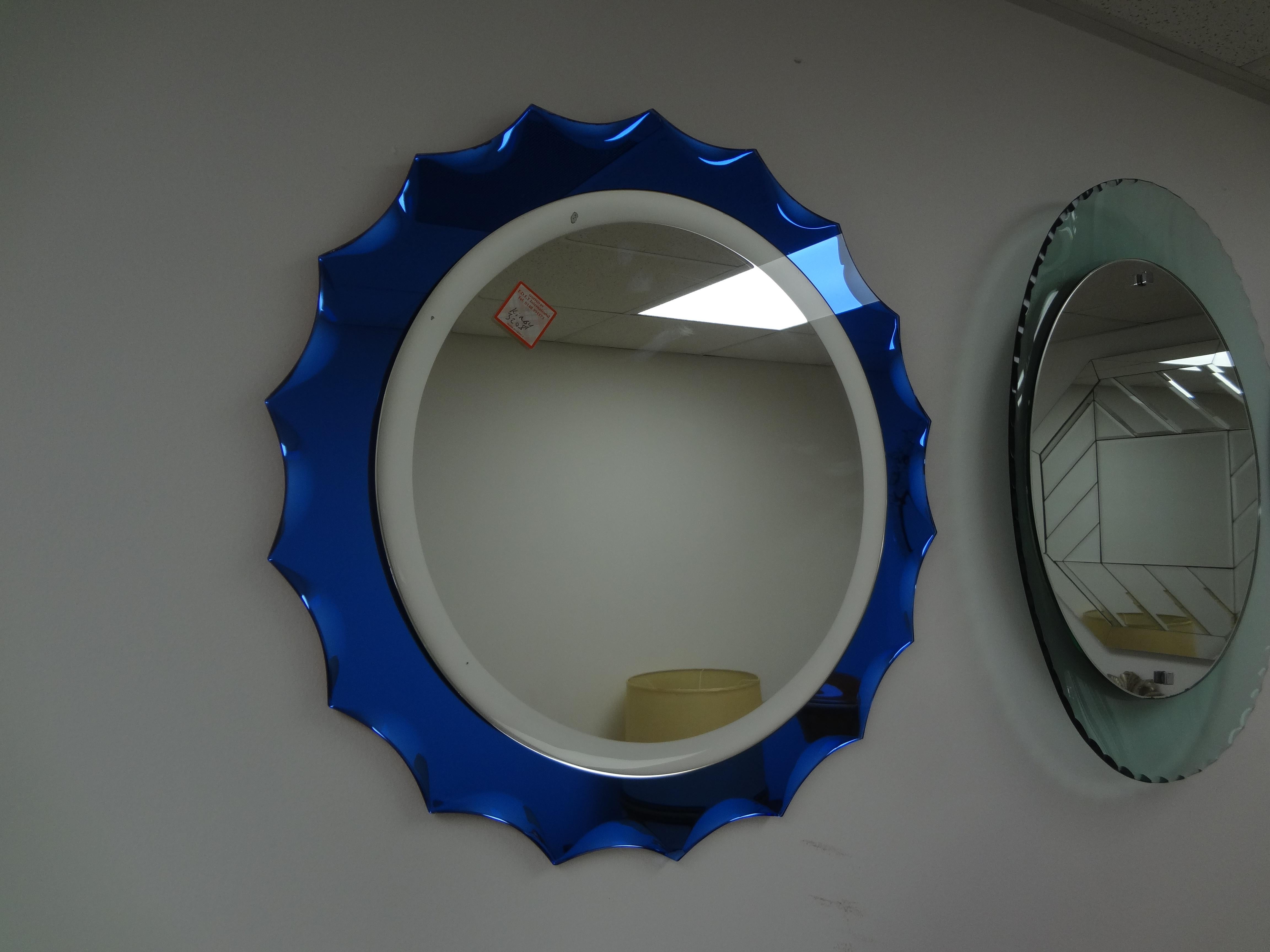 Italian Modern Fontana Arte Inspired Blue Beveled Mirror.
Shapely Italian mid century Fontana Arte inspired beveled mirror. This lovely vintage Italian beveled mirror has a stunning vibrant blue perimeter with a silver oval interior section. 
Great