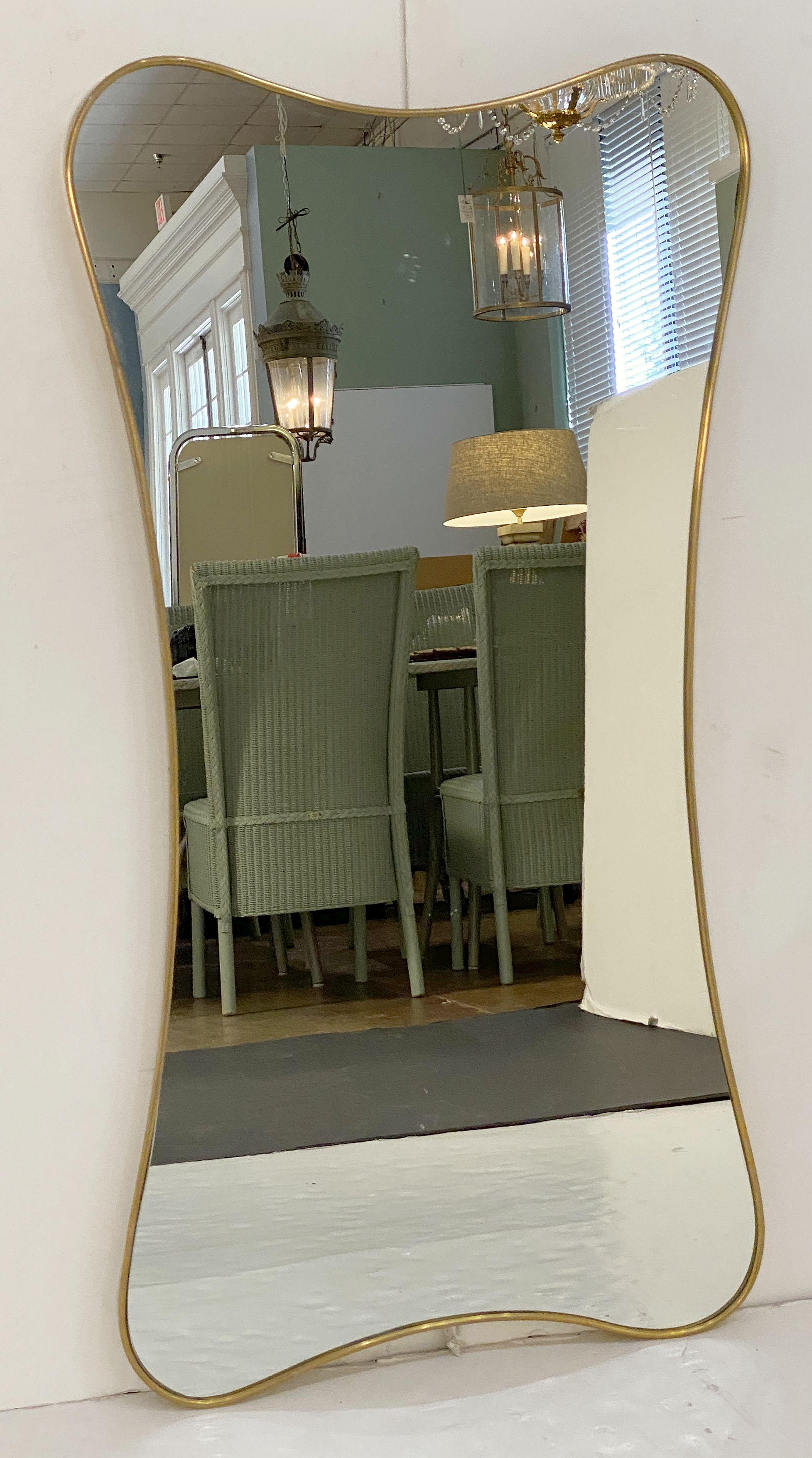 A fine Italian Modern wall mirror featuring a clean, Mid-Century design with an elegant, curved frame in brass, in the style of the famed designer, Gio Ponti. (Italian, 1891-1979)

An architect, furniture and industrial designer and editor, Gio