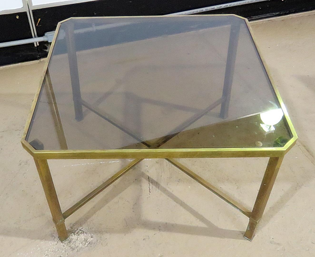 Italian modern coffee table with a smoked glass top on a brass X base.
