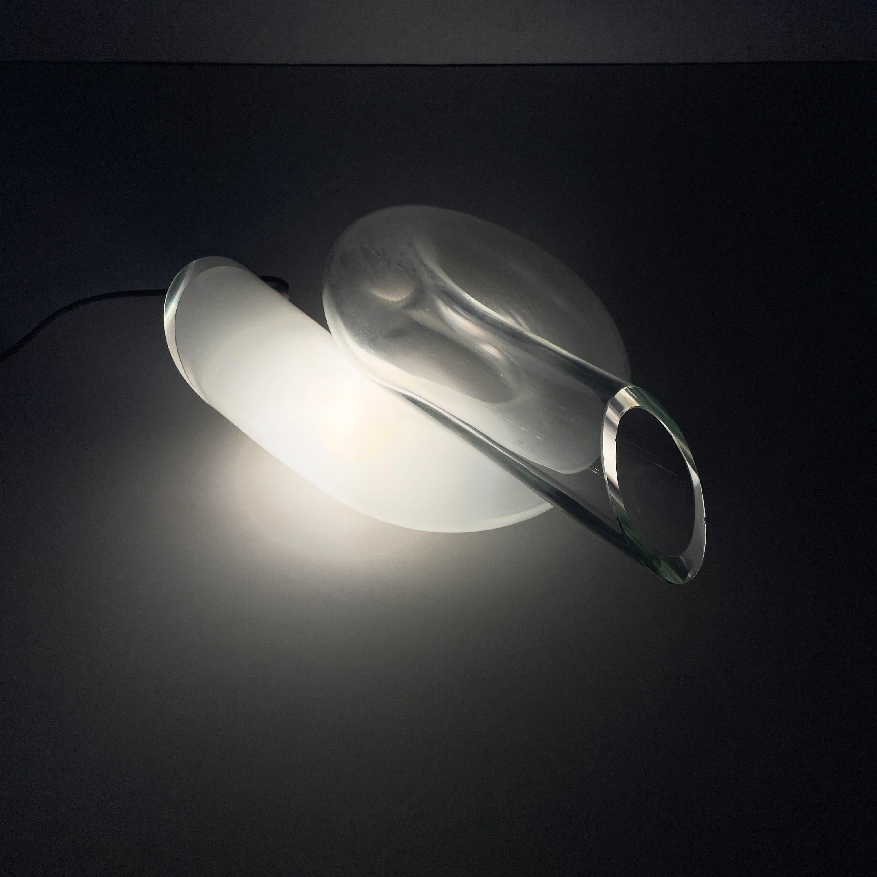 Lampe de table nouée moderne italienne en verre opalin et transparent, 1980
Lampe de table entièrement réalisée en verre épais qui passe du blanc au transparent. La lampe est constituée d'un tube de verre noué sur lui-même. Les extrémités du tube