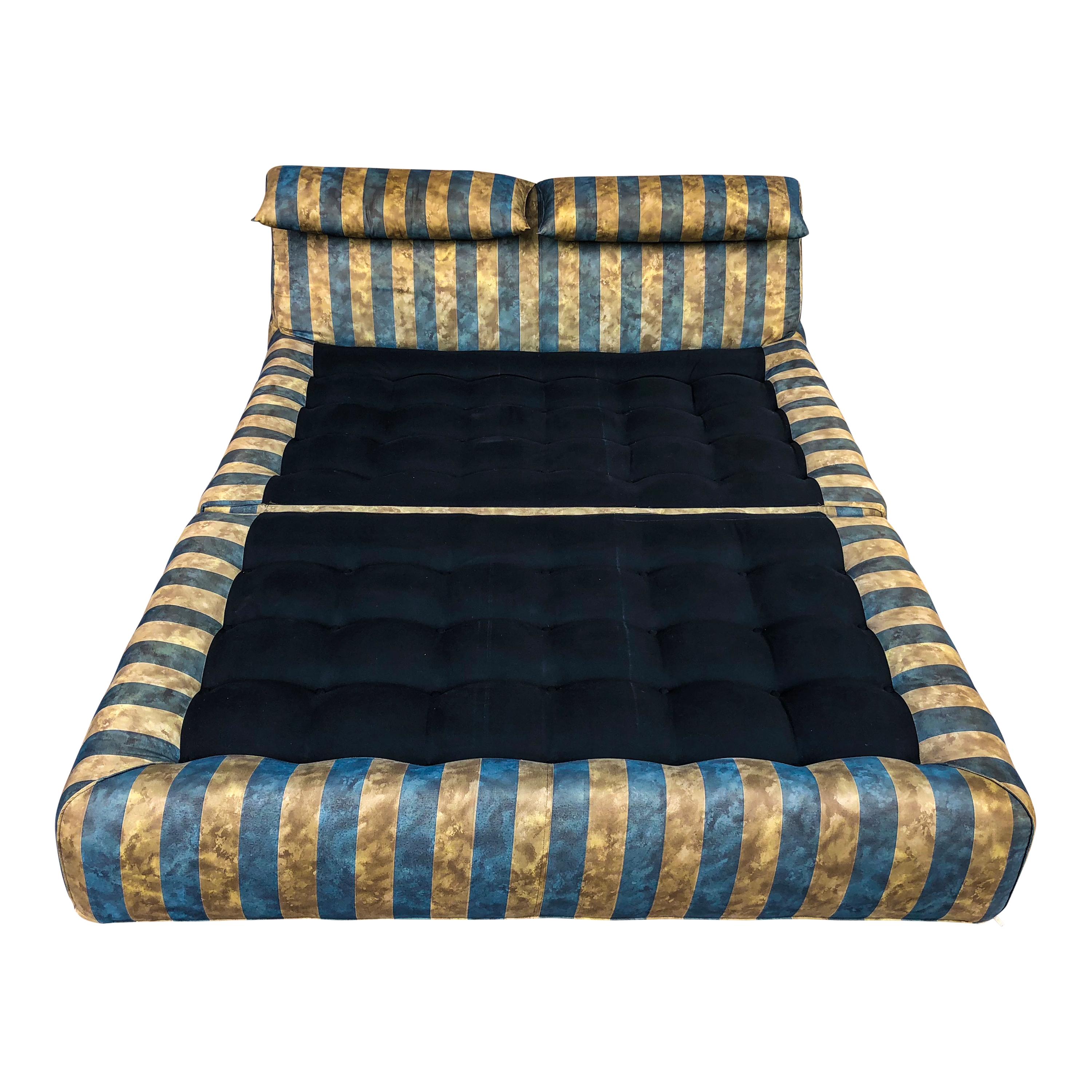 This Le Bambole day bed was designed by Mario Bellini in 1972 and manufactured by B&B Italia in 1976. It features a tubular steel structure, polyurethane foam and a blue and beige striped upholstery (with a particular pattern that give it a satin