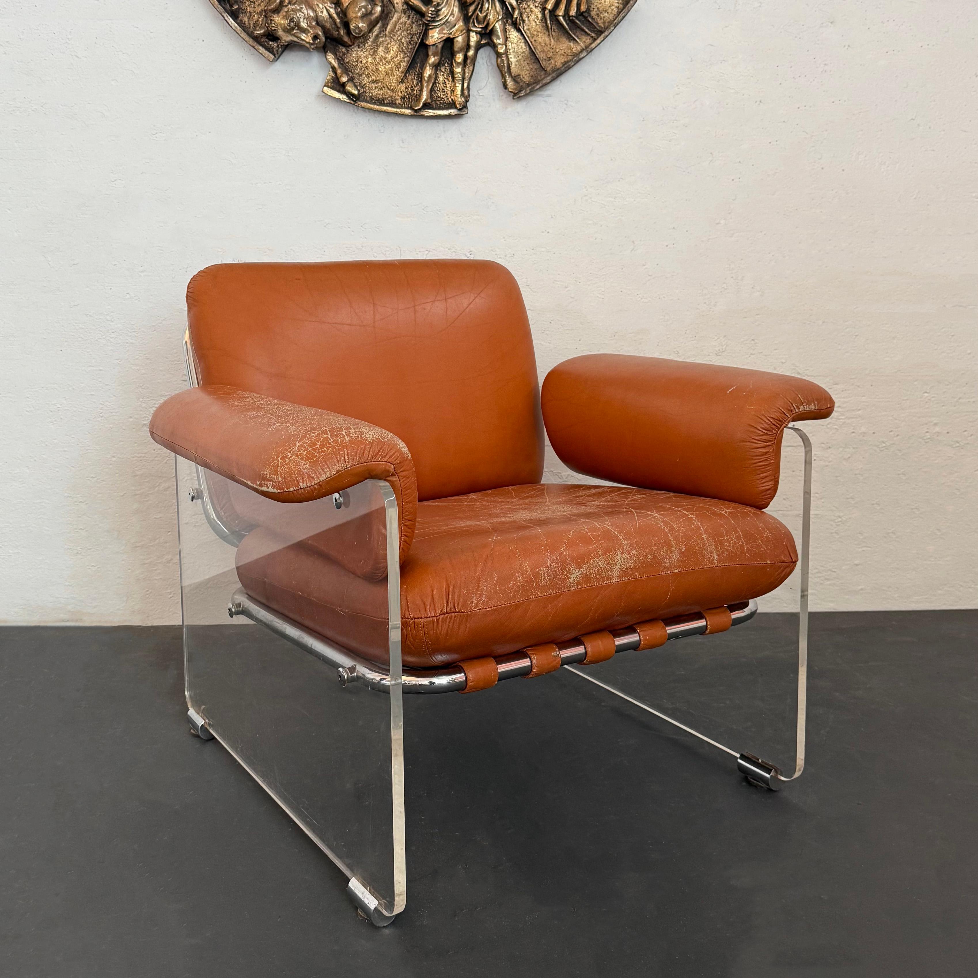 This Italian mid-century modern club lounge chair by Pol Flex Artegna features thick clear Lucite side panels with chrome details. Burnt orange Italian buffalo leather straps wrap around the tubular chrome frame to support the loose, patinated