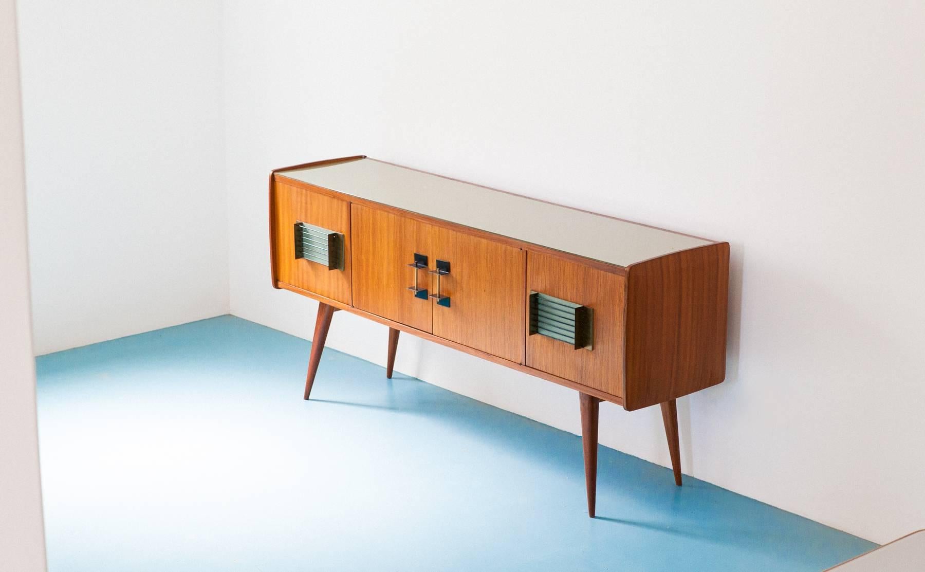 This modern sideboard was manufacture in Italy in 1950's
This Enfilade has a wooden cabinet that is  veneered in mahogany, the legs are in solid mahogany .The handles, which we believe to be the most interesting and particular part, were made of