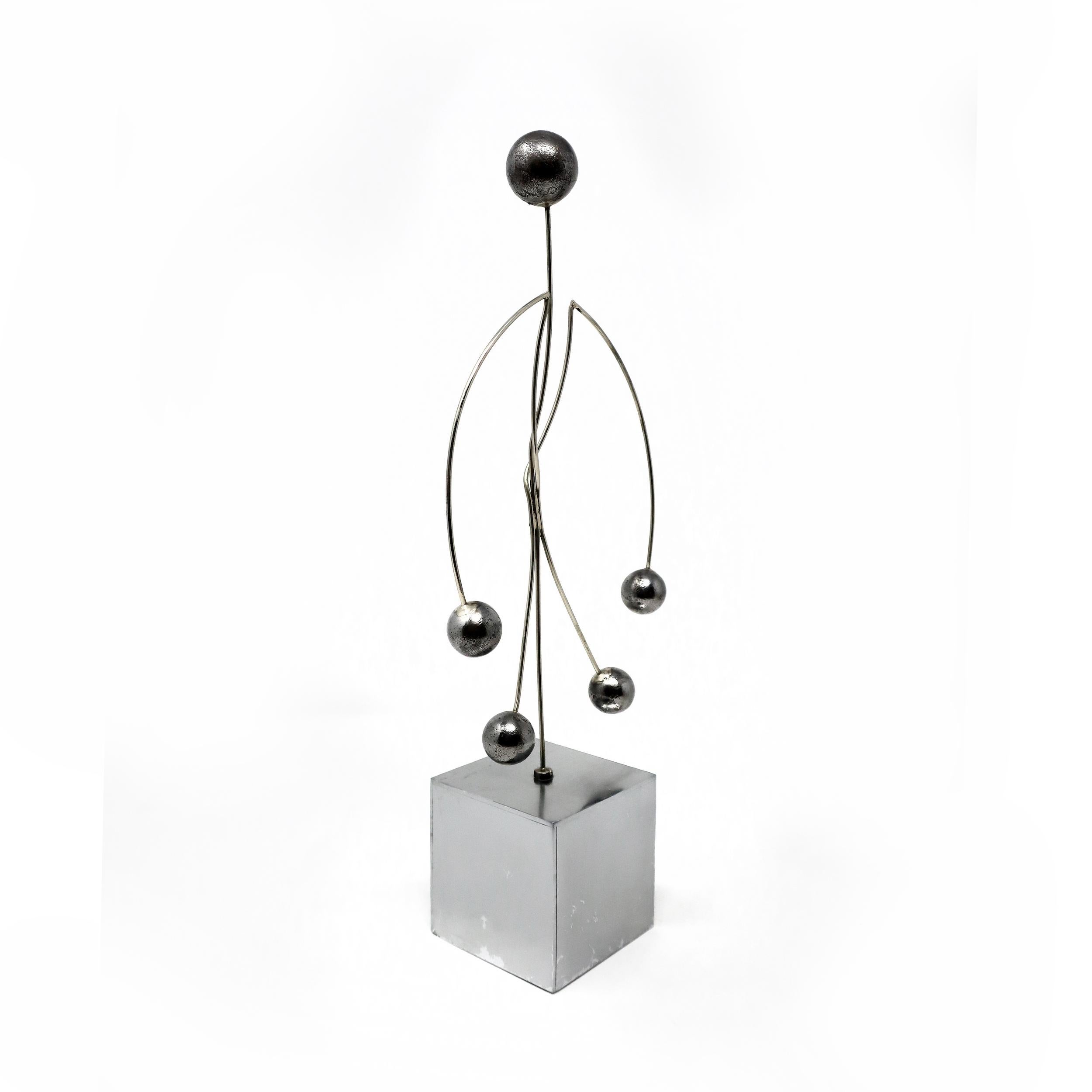 A vintage metal kinetic sculpture in the figure of a human body. Set on a weighted chrome base with a figure constructed from heavy gauge metal wire with weighted metal balls for hands, feet, and head. The weight of the limps and head give this