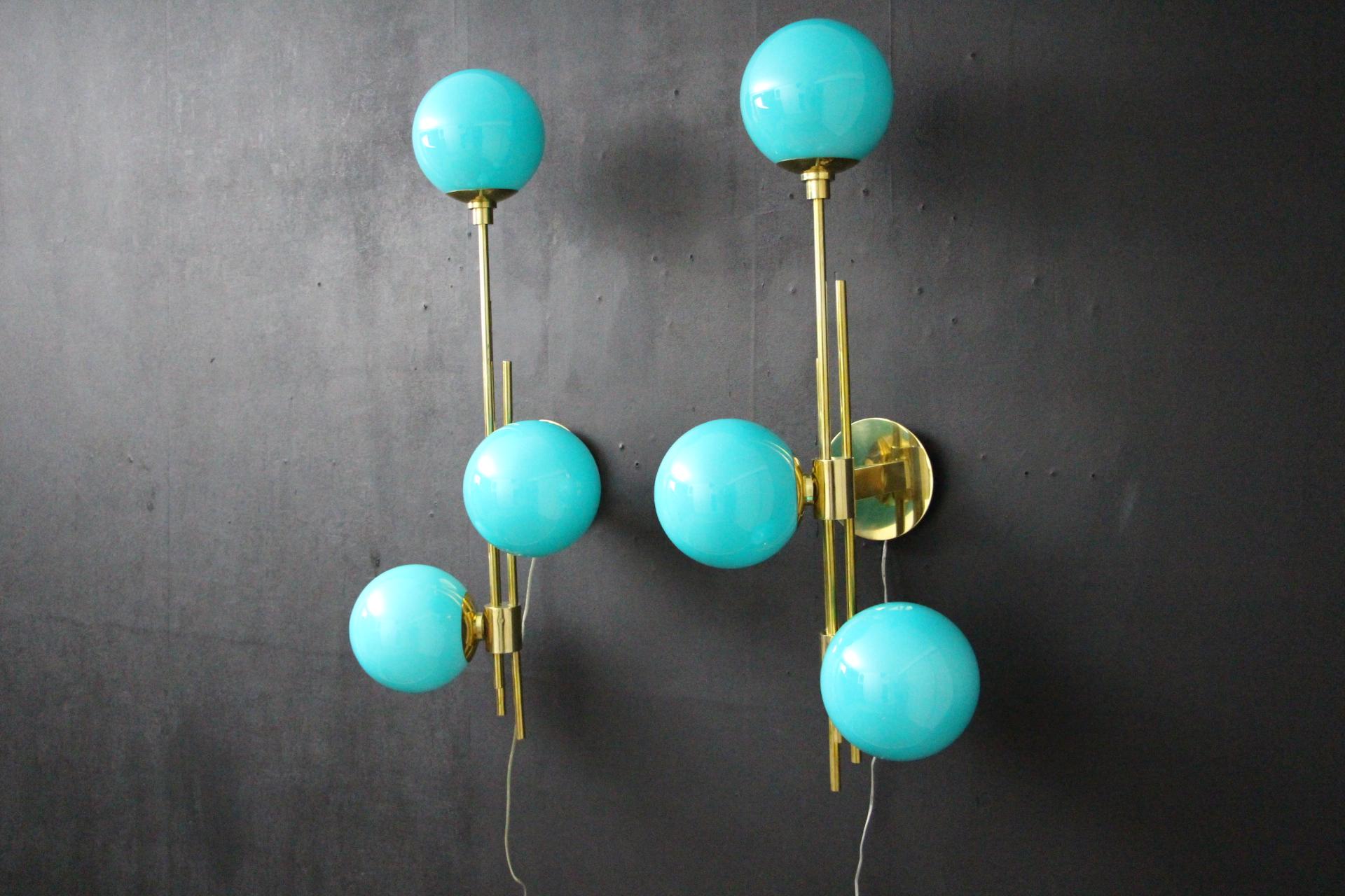 These sconces are very elegant with their brass frame and Tiffany blue Murano glass globes. They have got very unusual geometrical proportions and are absolutely gorgeous.
They could match with a very design interior or a typically mid century