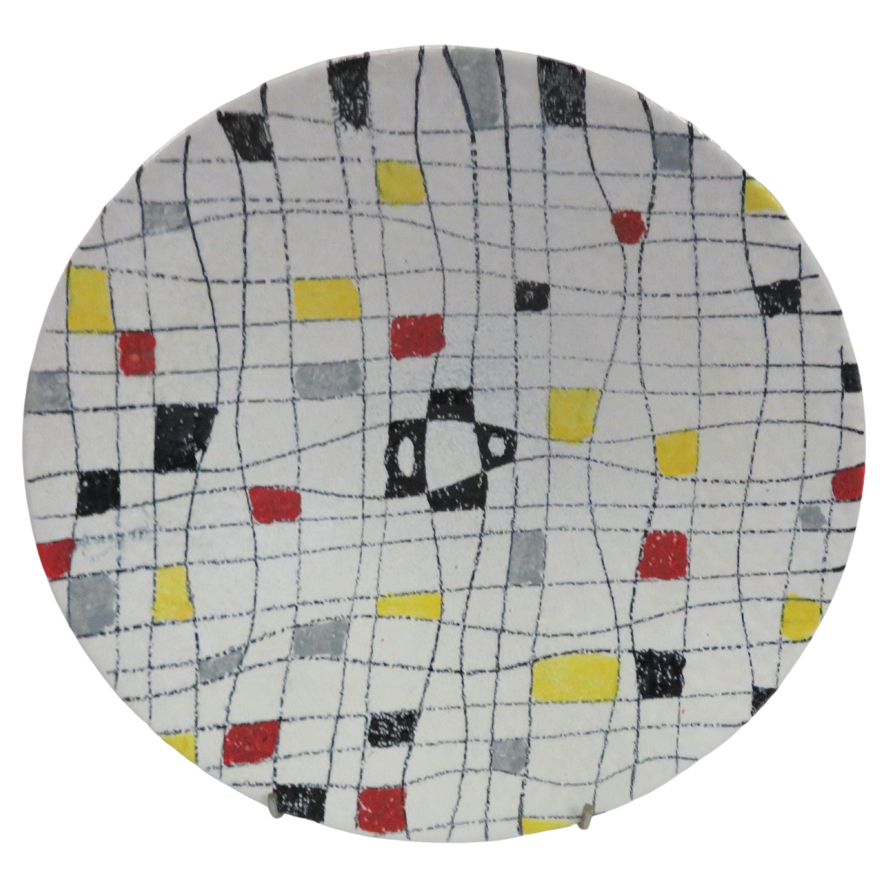A Mid-Century Modern offering attributed to Alvino Bagni for Bistossi, a footed shallow ceramic bowl vessel with a stylized crosword design of squiggly lines with block squares in red, yellow, gray blue and black on a white glazed soft textured