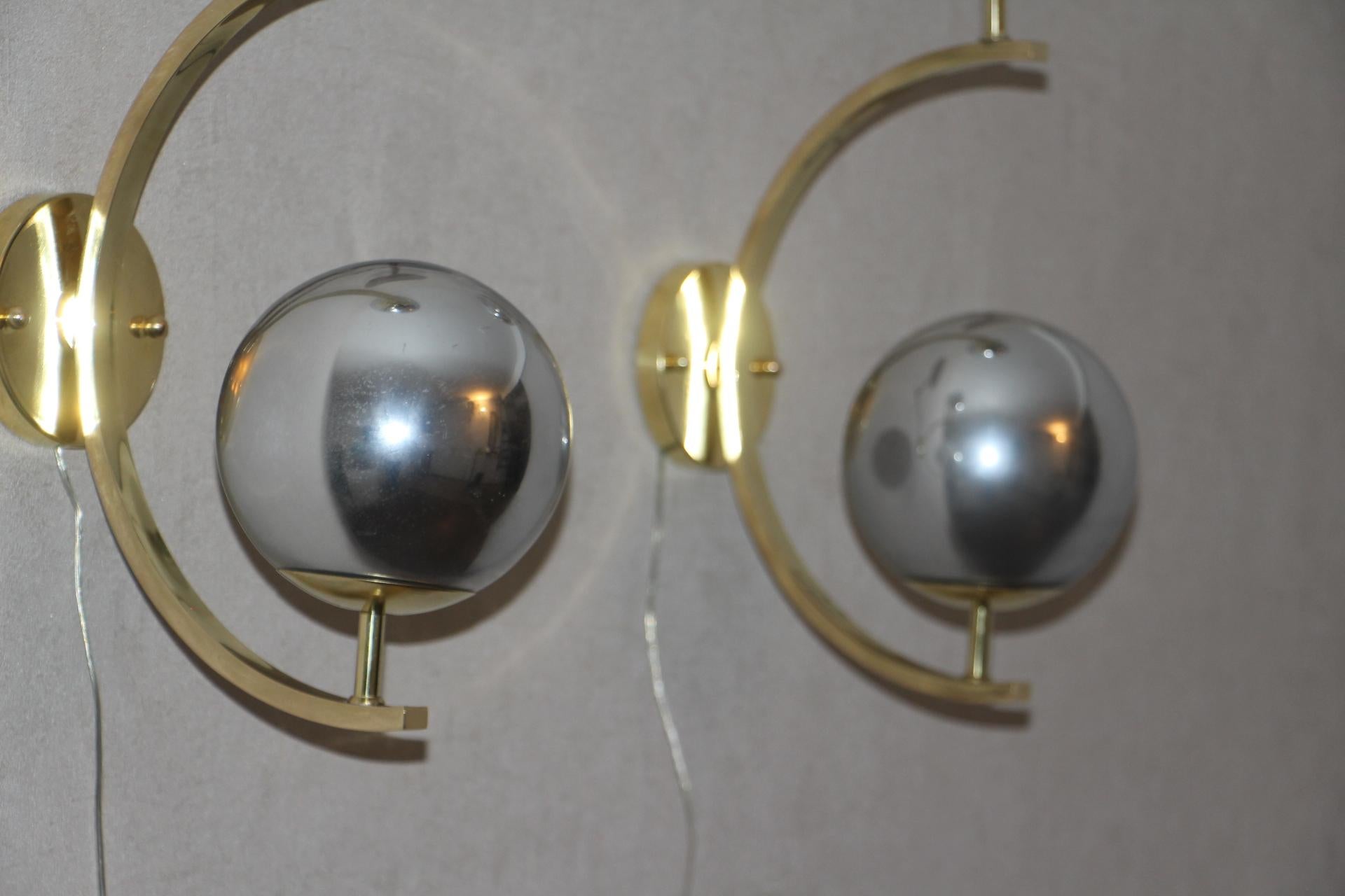 These sconces are very elegant with their brass frame and silver Murano glass globes . When light is off,they are completely silver mirror color and when light is on,they turn to irregular silver reflects. 
They have got very unusual geometrical