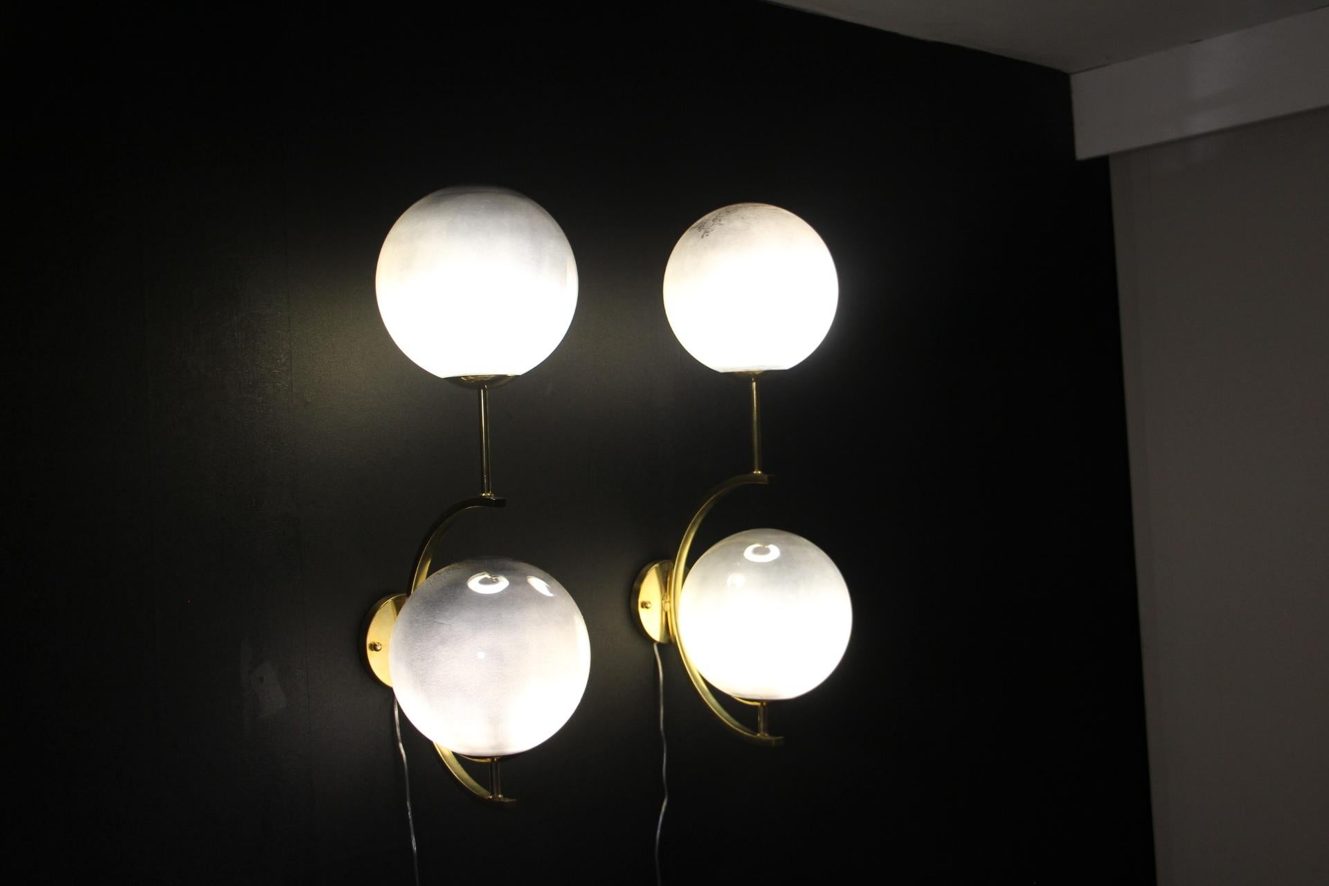 These sconces are very elegant with their brass frame and their large silver Murano glass globes . When light is off ,they are completely silver mirror color and when light is on,they turn to irregular silver reflects. 
They have got very unusual