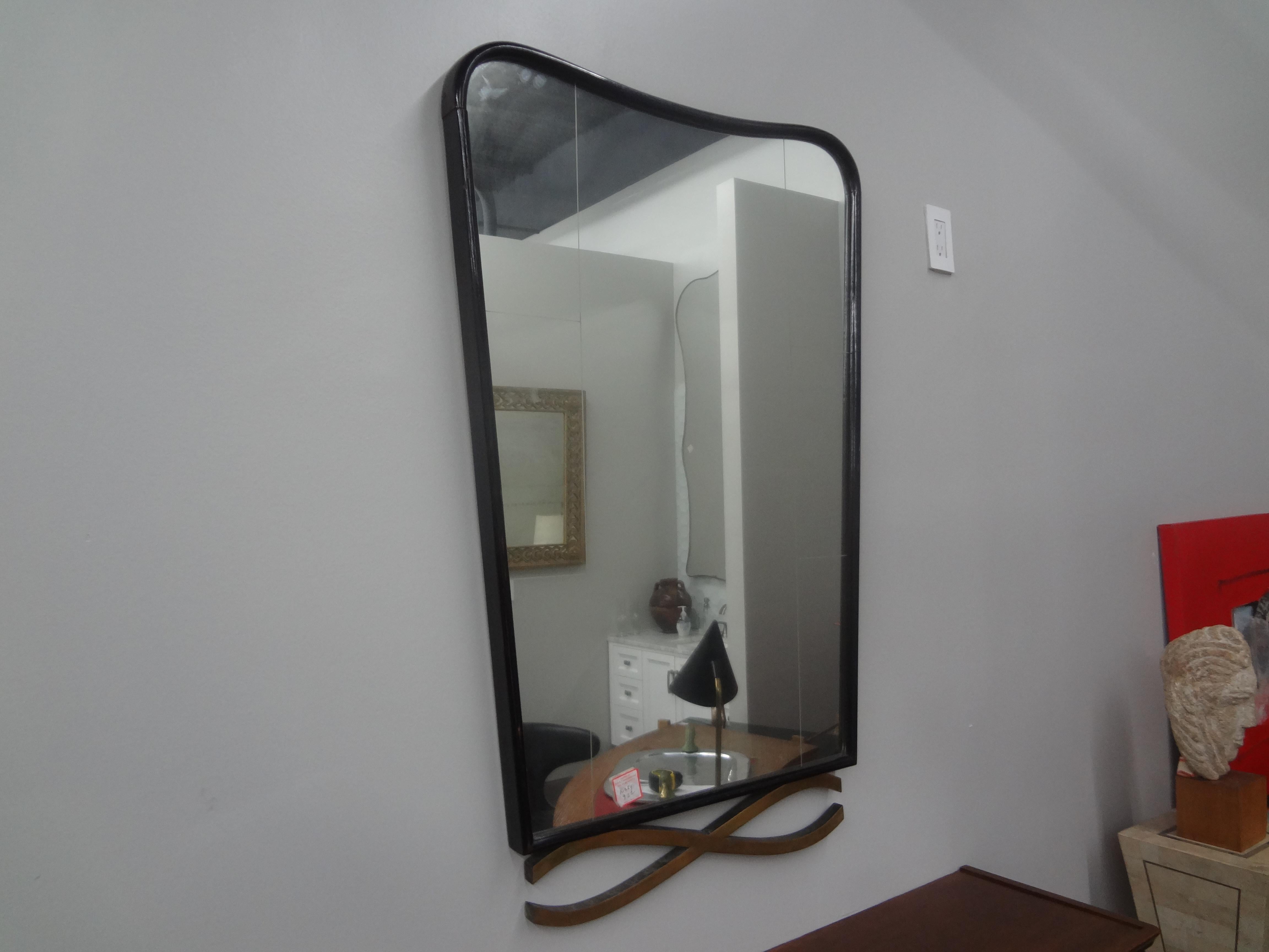 Moderner italienischer Spiegel, der Ico Parisi zugeschrieben wird.
Dieser formschöne italienische Mid-Century Modern-Spiegel ist aus Nussbaumholz gefertigt und hat ein ungewöhnliches, übertriebenes x-förmiges Bronzedesign an der Unterseite.
Der