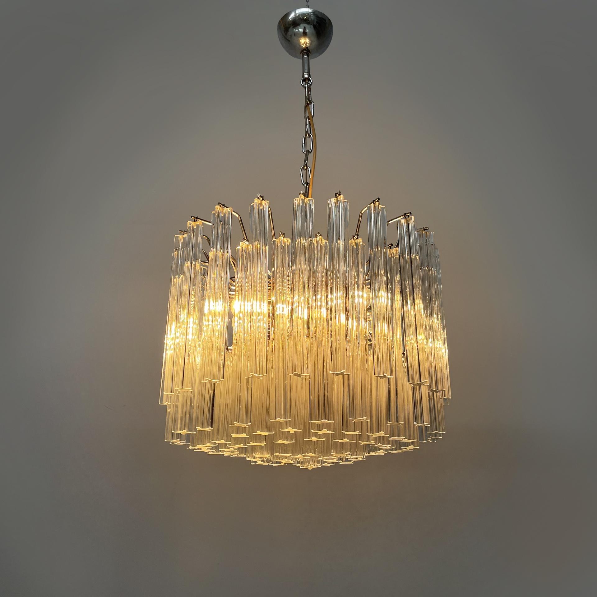 Lampadario moderno italiano in vetro di Murano Due, anni '70
Lampadario o lampada da soffitto con diffusore composto da numerose strisce di vetro sagomate, che vengono appese alla struttura rotonda centrale grazie a bacchette di metallo. La lampada