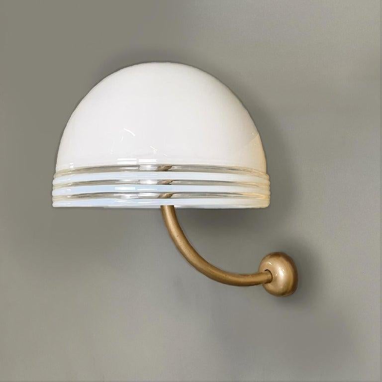 Italian modern Murano white glass and golden metal appliques by Leucos, 1980s

Pair of round base wall lamps. The diffuser is a hemisphere in white Murano glass, at the edges there are three decorative lines in transparent glass. The support